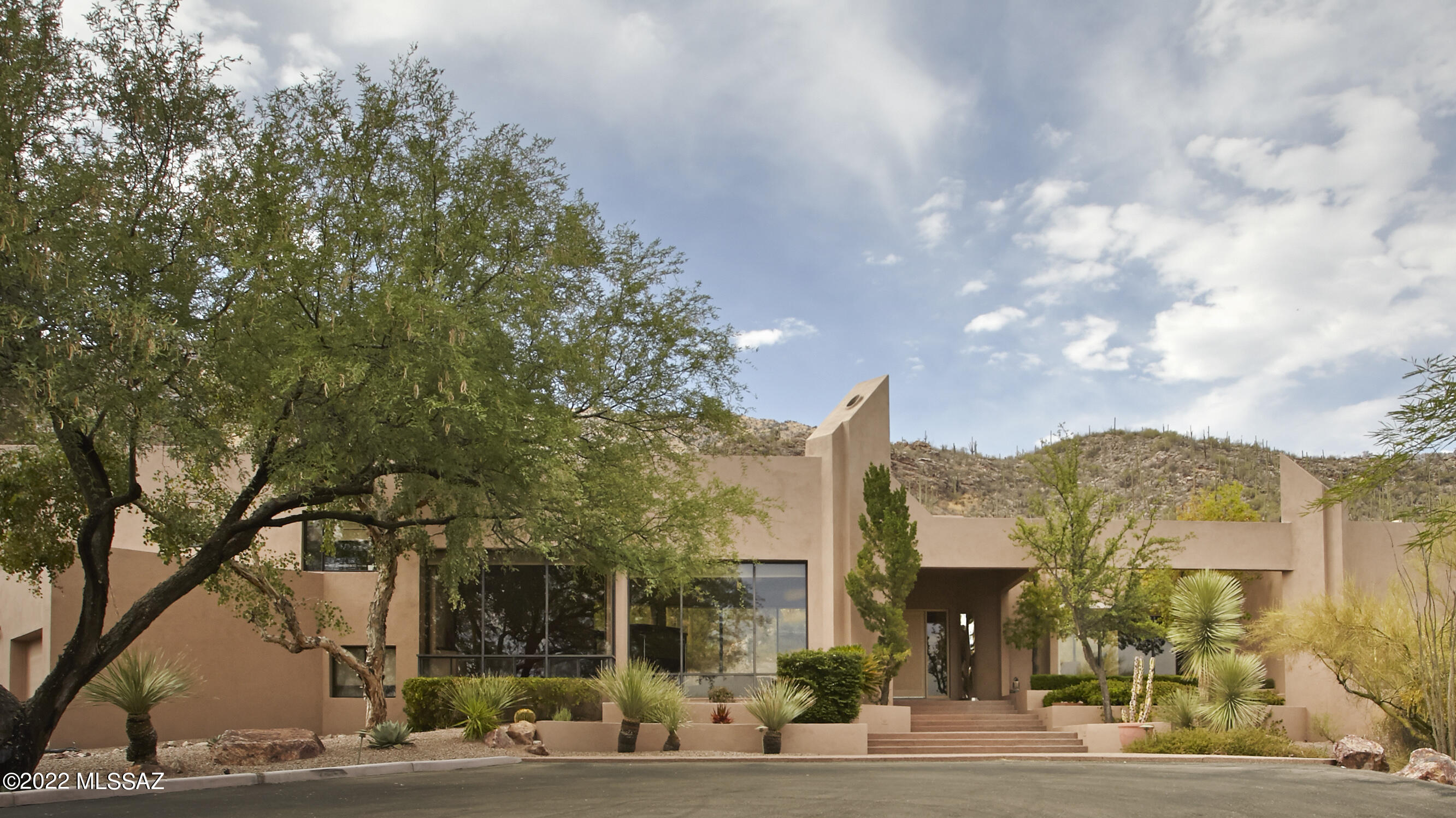 This exquisite architecturally unique contemporary home, on 1.6 acres, backs up to the Coronado National Forest in prestigious guard gated Finisterra Estates. An open concept design & floor to ceiling windows capture BREATHTAKING SWEEPING VIEWS OF THE SAGUARO STUDDED MOUNTAINS. The great room has 20' hi ceilings, walls of windows, a custom designed entertainment center, bar & fireplace. The dining room easily accommodates 12 guests. The kitchen is complete w/top of the line appliances, granite counters, a gourmet island, custom cabinetry, a walk-in pantry, a desk area & breakfast room. The master bedroom suite is on the main floor & features 2 lg walk-closets w/blt-in dressers. a luxurious bathroom w/a lg walk-in shower, a tub, dual vanities & exercise room or study. The additional bedrooms are very private.  Each has its own bathroom & walk-in closet. One of the bedrooms is currently being used as an office & has an off-the-wall bed.
Enjoy Tucson's outdoor lifestyle in the resort-like backyard featuring an inviting patio, a spa, professional landscaping, newly installed artificial turf, a blt-in BBQ & the unobstructed magnificent views. 
The 3 car garage has epoxy floors, lots of blt-in storage & a workroom. Community amenities include a clubhouse, heated pool, spa, tennis & pickle ball courts & security.  
Original owner. 
Very special property!