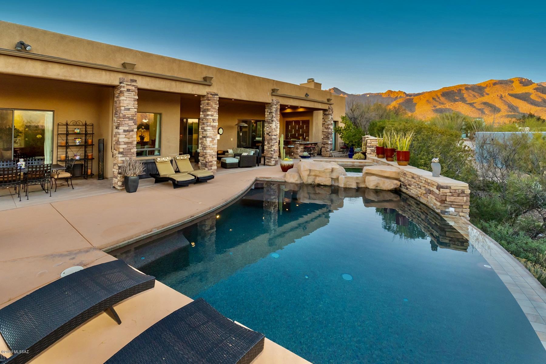 Just around the Corner from Canyon Ranch!Be prepared to be wowed in this custom soft contemporary home built In 2007.  The interior features, 12 ft ceilings, wall of windows to enjoy the incredible mountain views, scored/stained concrete floors. The kitchen is a show stopper w/Viking appliances in deep plum, custom stained cabinets, thick purple dune granite, lg center island. This expands into the great rm w/custom wood entertainment center. Master br, has gas fireplace, jacuzzi tub,& lg walk in closet. All 4 br.  are generous in size w/ensuite baths, & African mahogany floors. The backyard is the perfect balance of indoor/outdoor living w/ heated salt water negative edge pool/spa! Outdoor Kitchen w/granite counters, BBQ grill, burner, & sink & wood burning fire pit. Perfec Plenty of storage in this home. Large walk in closets in each br. Walk in Pantry, as well as a butlers Pantry. Laundry room has wine refrigerator, storage closet and cabinets. Shelves in garage will convey. Reverse Osmosis, water softener through out. Alarm system is owned. Solar is leased, ask about lower electric bill.