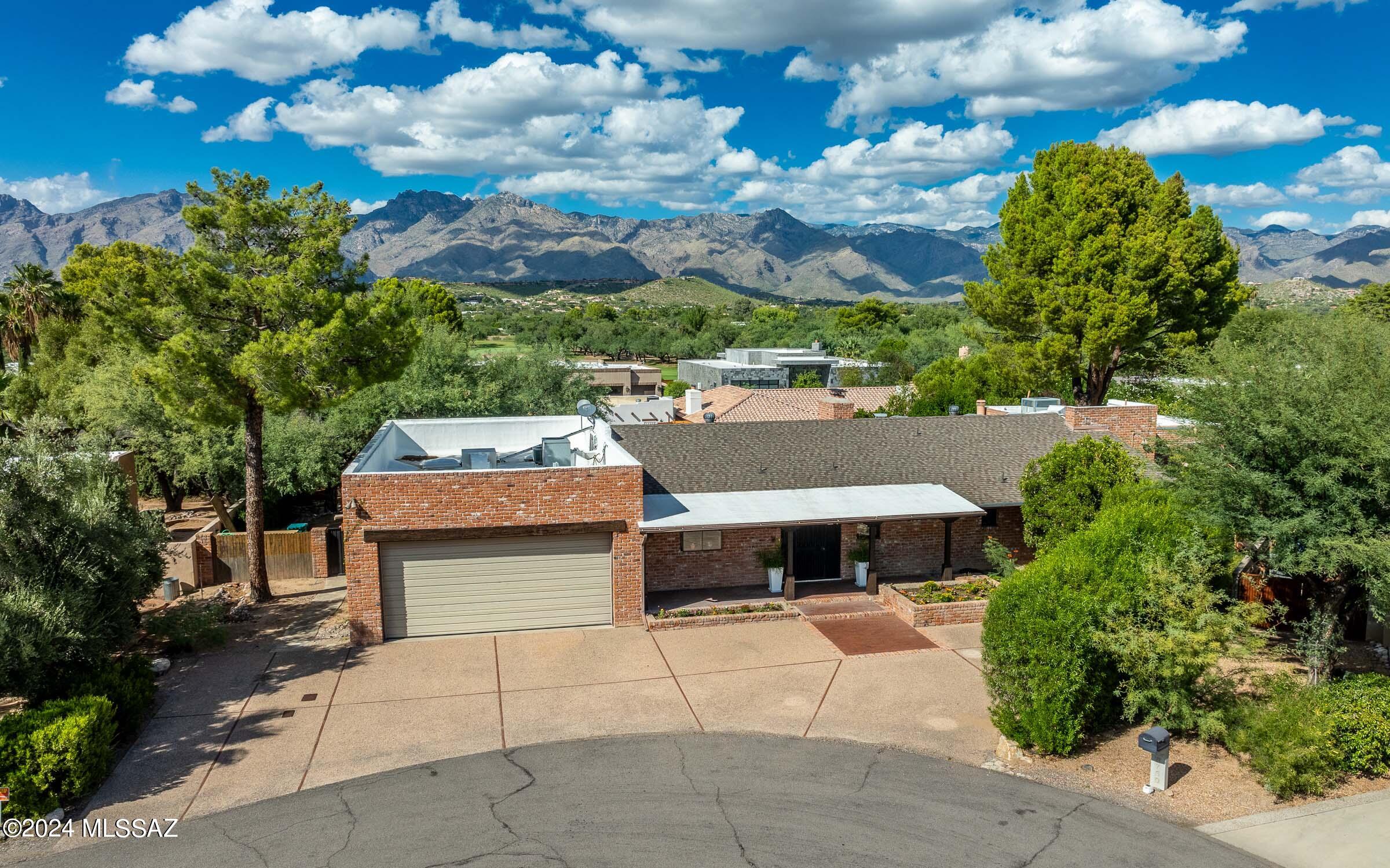 First time on the market! Come see this wonderful updated 4 bed/3 bath +Den brick home with outstanding views of the Catalina Mountains, oversized 42' long RV garage & huge finished basement on a quiet cul-de-sac in gated Tucson Country Club. This home exudes warmth with leaded-glass windows, custom wood trim, brick & wood flooring and cozy fireplaces. Three spacious bedrooms upstairs plus a 4th bedroom downstairs along with a bonus den. Gaze at the view from your back porch to the soothing sounds of the waterfall. Host Game Night in the high-ceilinged basement, large enough for a ping-pong table, a complete home gym or a whole separate living space. Bonus walled yard space could be a dog run, playground and/or pool with a view. So much to offer, so many possibilities Take advantage of this rare opportunity to own a spacious home with a finished basement in the private and gated Tucson Country Club Estates. Located on a cul-de-sac that limits traffic and noise in the direct area, the home is conveniently located close to the club house and part of a larger community with holiday events and block parties. This spectacular residence with over 4,600 square feet of living space is perfect for families needing extra space to spread out, those frequently hosting family/friend visitors and/or entertainers looking for large rooms to host events.
 
The recently renovated kitchen features new appliances, including an induction stove top, exposed brick backsplashes and columns, and additional counter and cabinet space with the added peninsula. The garden window facing the front of the house allows you to grow your favorite herbs for cooking, while looking out into your front yard flower beds. 
 
The large primary bedroom includes a walk-in closet that is nearly a room in itself, a bathroom with new shower and plenty of space, and an adjoining office with backyard access. The second bedroom on the primary floor also features a walk-in closet, and a newly updated adjoining bathroom.
 
Brick flooring is prominent throughout the primary floor, including the expansive dining and great room that flow out onto the backyard porch. Whether you are in this room, the primary bedroom, primary bathroom or adjoining office, you are surrounded by picturesque views of the Santa Catalina Mountains and the colorful backyard gardens. The higher elevation and north-south exposure allows for panoramic views of the mountains and vibrant Tucson sunsets.
 
With a total of three den/office spaces, one of which is ready to be used as a third bedroom including an intra-room closet, you have multiple spaces for a home office, gym, playroom or whatever fits your family's needs the best.
 
In addition to the den, bedroom/den and storage space, the finished basement also includes a third bathroom and a sizable room with heigh ceilings that can used as a family room or entertainment area. Whether you want to host large family gatherings or have a family theatre room - this rare open-space provides you the flexibility to consider many options. In addition to the 4,646 square feet of living space, the home also includes an abundance of storage areas adjacent to the three-car garage and the unfinished basement.
 
The backyard includes beautifully landscaped mature vegetation on an irrigation system and the serene sounds of a waterfall fountain. In addition to the large-landscaped area, the backyard has an additional space that provides the opportunity for you to build whatever your imagination will allow. With plenty of space for a pool, play area or backyard entertaining, this blank canvass enables you to make it your own.