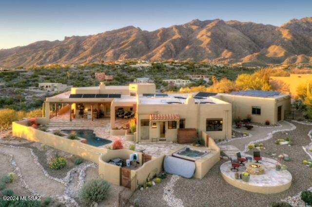Nestled atop a ridge in the esteemed Cimarron Foothills Subdivision, this magnificent Santa Fe style home offers unparalleled luxury and breathtaking panoramic views of not just one, but four mountain ranges. From every window, immerse yourself in the splendor of the Catalinas, Rincon's, Tucson Mountains and Santa Ritas, while being treated to spectacular sunsets that paint the sky with hues of orange and gold. This unique residence boasts an array of amenities to enhance your lifestyle. In addition to the main living area, this home features a private downstairs guest quarters complete with a living room, bedroom, and bath. With its  own entrance, your guests will enjoy comfort and privacy, making every stay unforgettable. Step outside into the expansive backyard oasis and discover your personal retreat. Relax and rejuvenate in the inviting hot tub as you soak in the serenity of the surrounding natural beauty. Whether you're entertaining guests or simply unwinding after a long day, the outdoor haven is the perfect setting for creating cherished memories. Multiple patios provide ample space for outdoor entertaining or quiet relaxation, allowing you to fully embrace the tranquility of desert living. Inside, the home exudes Southwestern charm with intricate mosaic details and Saltillo flooring. Recently upgraded, the spacious open kitchen boasts new cabinets, elegant quartz countertops, and slate appliances. Formal dining area & living room with beehive fireplace provide functional spaces for easy care living. Practical features such as electric and gas water heaters, a water softener and updated windows ensure convenience and efficiency. The primary bedroom offers ceramic flooring for easy maintenance, while downstairs quest quarters provide additional versatility and functionality. Entertain with ease in the BBQ area with a granite top, or cozy up around one of the two gas fire pits strategically placed in tranquil sitting areas. The resurfaced pool, travertine surrounds and soothing waterfalls provide a luxurious retreat, complemented by the new pool equipment including solar heating for year-round enjoyment. With a new roof and skylights illumination the home with natural light, and a 9.00 kW owned solar system installed by local experts, this residence seamlessly combines luxury with sustainability. Don't miss the opportunity to experience the epitome of Tucson living in this ridge-top sanctuary.