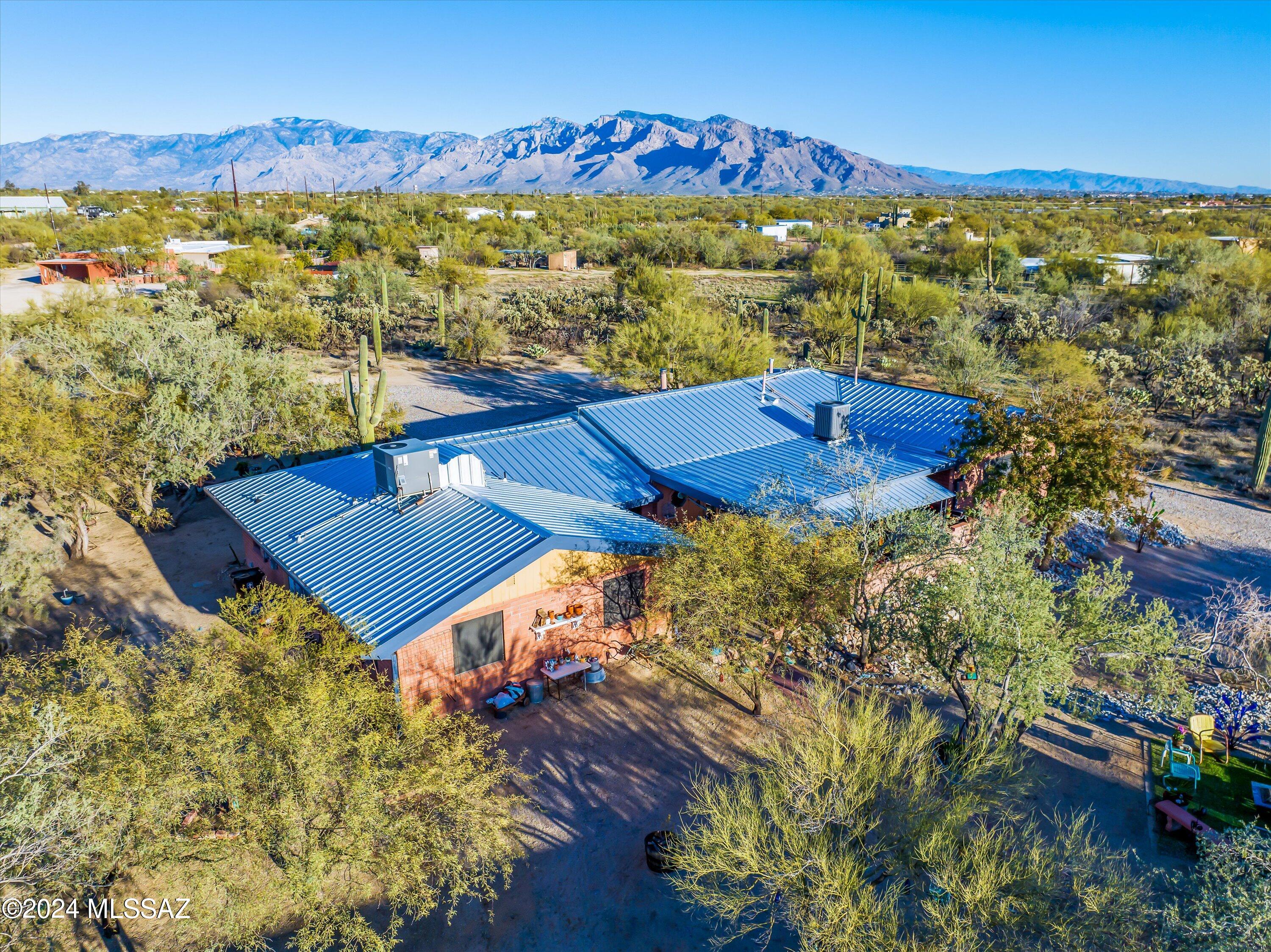 Privacy, Charm, & Character are hallmarks of this serene split bedroom home located within a manicured natural desert setting amongst shade trees and saguaro cacti.  Enjoy relaxing on the shady patio and gazing at the mountains from the kitchen and great room with high wood beam ceilings.  One wing of the house works well as guest quarters.  The large Concrete block shop/garage is 25'X45' in size and has a tall roll up door. The RV port is a 30AMP with dump station.  Two gates allow easy access without having to turn around or back in.   You can feel secure under the fully guttered standing seam steel roof and save on electricity with the owned PV solar array.