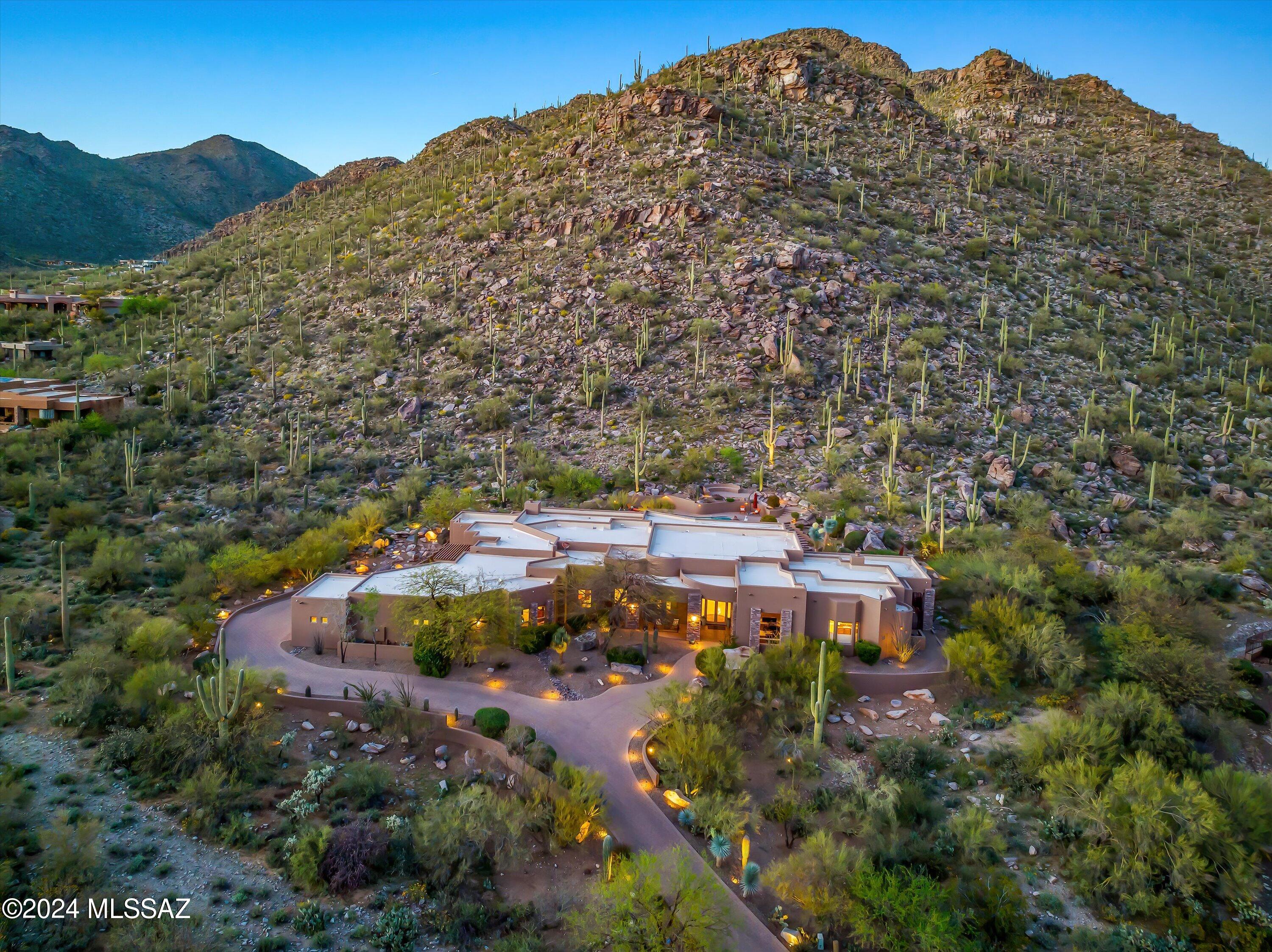 Located in exclusive Canyon Pass in Dove Mountain, this captivating desert contemporary home sprawls over 1.8 acres of stunning landscape and mountain views. Boasting an expansive dream kitchen with Viking appliances, wet bar, and temperature controlled wine room. Enjoy seamless indoor-outdoor living with automatic disappearing glass door, large media room with fireplace and lavish primary suite with Miele coffee station, fireplace and spa like bath and large custom walkin closet. Entertain effortlessly with outdoor delights including a sparkling pool, rock waterfall with dipping pool, outdoor bathroom and putting green, all complemented by an outdoor kitchen and firepit. Other highlights include soaring ceilings, natural stone and wood floors, and smart home features with automation, a robust security system, and oversized 4 car garage and bonus room. Experience an unparalleled blend of sophistication, comfort and privacy.
