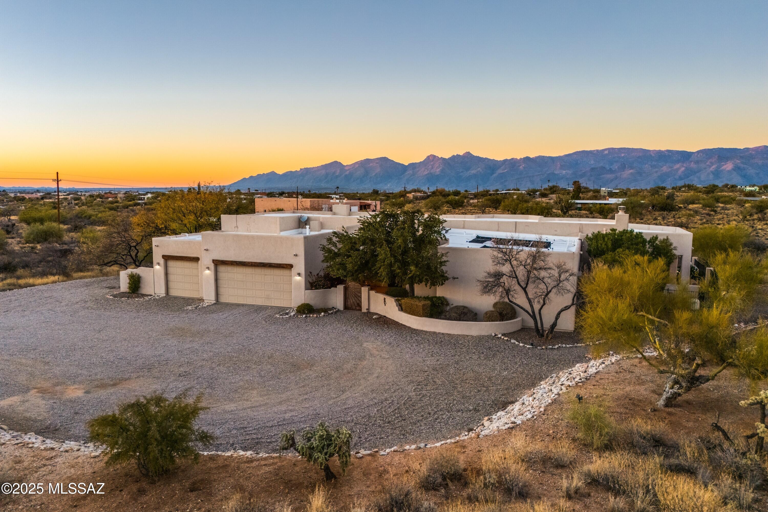 Stunning Santa Fe Retreat with spectacular Mountain Views Nestled in the heart of the pristine Sonoran Desert, this spectacular Santa Fe-style home is perfectly situated on a sprawling 4-acre parcel, offering unparalleled, panoramic views of the Catalina and Rincon Mountains. A grand courtyard entry welcomes you with a custom wrought iron gate and door, beautifully accented by wood corbels and lush, mature landscaping—setting the stage for the elegance that awaits inside. Step through the entryway and be greeted by soaring 12-foot ceilings, wood corbels, and French doors and windows that frame the breathtaking desert vistas. The expansive kitchen is a chef's delight, featuring rich Alderwood cabinetry, stainless steel appliances, and a five-burner gas cooktop set in a custom niche adorne with Talavera tile accents. Elegant granite countertops, a tile backsplash, and a breakfast bar overlook a cozy breakfast nook with picture-perfect windows, creating a warm and inviting space. Adjacent to the kitchen, a spacious family room boasts a corner beehive fireplace, a built-in entertainment center, and a picture window framing the stunning Rincon Mountains. The primary suite is a private sanctuary, offering a tranquil corner fireplace, sliding glass doors, and a clerestory window that floods the space with natural light. Step outside to enjoy private backyard access and take in the serenity of the surrounding landscape. The spa-like en suite features a double vanity with Talavera sinks, a corner soaking tub, a separate walk-in shower, and a generous walk-in closet. Designed with privacy in mind, this architecturally pleasing split-bedroom layout offers generously sized bedrooms, most with walk-in closets, and a convenient Jack-and-Jill bathroom. The expansive wraparound patio is an entertainer's dream, offering unobstructed Catalina and Rincon Mountain views. A sparkling pool, an elevated spa with a soothing water feature, and a built-in BBQ area create an idyllic setting for relaxation. Whether you're admiring the twinkling night skies or the brilliant blue daytime skies, this space is designed for year-round enjoyment. Modern rolling shutters on all windows and doors (except front door) provide added security and peace of mind while traveling, easily controlled with the touch of a button. The spacious laundry room offers granite countertops, built-in cabinetry, and a laundry sink for added convenience. A three-car garage with a dedicated storage room ensures plenty of parking and organization. This home checks every box, offering privacy, breathtaking views, and expansive living spaces in an unmatched desert setting. Don't miss this extraordinary opportunity!