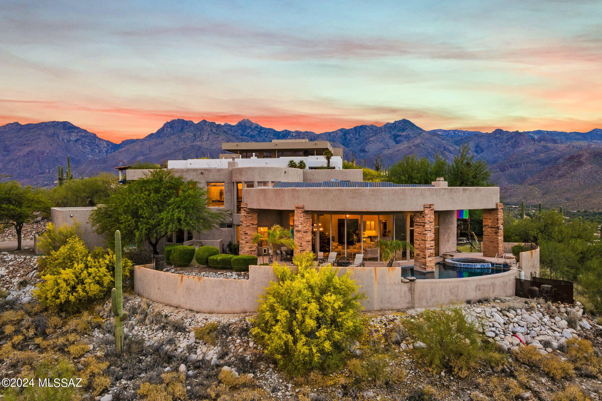 Views that this house offers are like no other! Enjoy City Lights AND Mountain Tranquility at once.  This Contemporary, Luxurious home sits perched above the Tucson Valley. Floor to ceiling windows with mostly automatic shutters and an open floorplan creates a feeling of seamless indoor and outdoor living.  Custom kitchen has quartzite counters/Island, Banco sink, Stainless Steel Viking and GE Profile appliances & Alder + Mample Cabinets.  Primary suite features fireplace for cozy Tucson nights, spacious yet functional bathroom, exercise/office with door leading to a balcony.  Washer and Dryer in primary closet for convenience!  Three ample size bedrooms downstairs, two with ensuites, custom built ins, walk in closets.  Security shutters on two of the bedrooms downstairs, Owned Solar Panel.   Backyard is an absolute oasis with wrap around patio, infinity pool overlooking the city, yard areas on both sides.  Please see documents for all the features of this home