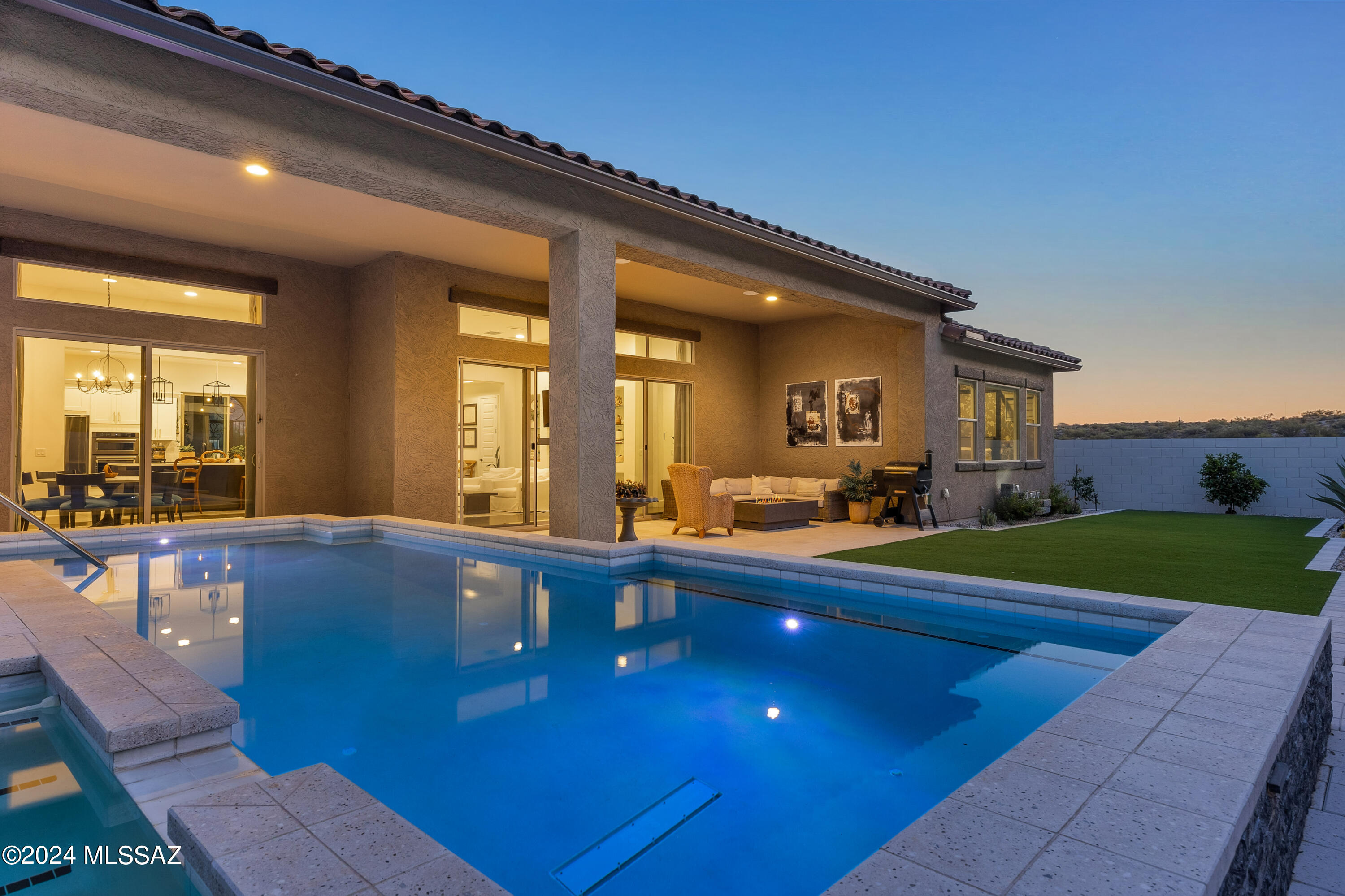 Exceptional 2020 home situated on a premium view lot in gated Alterra at Vistoso Trails near Stone Canyon in Oro Valley. Over $400,000 in upgrades & improvements. A true desert sanctuary, this elevated homesite delivers unobstructed views of saguaro-studded hills & unparalleled privacy. A driveway lined w/ pavers leads to impressive wrought iron doors that open to a courtyard w/ terrazzo-style pavers, mature vegetation & the sound of water from the fountain. This dynamic space sets this home apart from the others by providing a buffer from the street, a beautiful view from the kitchen & a protected space for alfresco dining, entertaining, or enjoying the AZ weather.  Experience modern living to the fullest w/ flawless contemporary design coupled w/ a thoughtful layout CONT... that maximizes the use of space. Inviting entry w/ gallery walls is bright & airy. The open great room has high ceilings, real hardwood floors, a modern gas fireplace, LED lights & a 16-foot sliding glass door that opens to the backyard to facilitate the indoor/outdoor Arizona lifestyle effortlessly. A huge waterfall quartz center island w/ a breakfast bar connects the kitchen, great room & formal dining area for ease of living. The chef's kitchen offers granite counters, a farm-style sink, upgraded cabinetry w/ drawers for pots & pans, and black stainless-steel Kitchenaid appliances. Additional kitchen features include chevron pattern tile floors, a modern tile backsplash, a pot-filler, and a big walk-in pantry w/ built-in shelves. A sizable mudroom just off the kitchen for dropping bags, backpacks, shoes & more leads to the oversized, tandem 3-car garage.  The tasteful primary suite offers the style & comfort of a luxury hotel suite. Spa-inspired primary bath is a soothing space to restore & relax. Striking, custom shower with glass enclosure, soaking tub, and dual vanities & sinks. Huge walk-in closet w/ built-ins connects to oversized laundry room w/ a closet, storage cabinets & sinkwell-placed powder room for guests just off the foyer. The separate guest wing begins with an ensuite guest room w/ a custom tile shower w/ a glass enclosure. The guest wing is unified by the "teen suite" the owner uses as an art studio. The 12-foot sliding glass door provides direct access to the front courtyard & wonderful natural light to this bonus room that can be an office, kids' playroom, workout room, or whatever suits you.  Two additional guest bedrooms with mountain views and an upgraded guest bathroom with a dual sink vanity and tiled shower& tub complete the floor plan. The backyard is a zen paradise defined by the modern desert landscape that is equally beautiful & efficient. A deep covered patio lined with pavers that spans the length of the back of the house is easily accessible from the great room & kitchen.  A built-in gas fire feature keeps you warm to enjoy a starry desert night outside. The new pool is partially under the covered patio, providing shade and protection from the sun, and has a spa. Artificial turf provides a pop of color and a place for kids and dogs to play without the high cost of maintaining grass. This next-level outdoor space is set amongst magnificent old-growth saguaro cactus on a protected hill for the ultimate privacy. In addition to the gate, the community features include a massive park area with grass, ample parking, covered playground equipment & bathrooms.  There is a separate dedicated space for the dog park. 
Highly-rated Oro Valley Schools nearby, Painted Sky Elementary school is just 5 minutes away. Just minutes from the famed Stone Canyon Golf Club and a myriad of top-notch golf courses. Oro Valley offers incredible parks, nature preserves, walking and biking paths, the Oro Valley Aquatic Center, and libraries. This home is close to Catalina State Park, with endless trails, natural desert beauty and several events throughout the year. Incredible restaurants and a plethora of stores are close by.