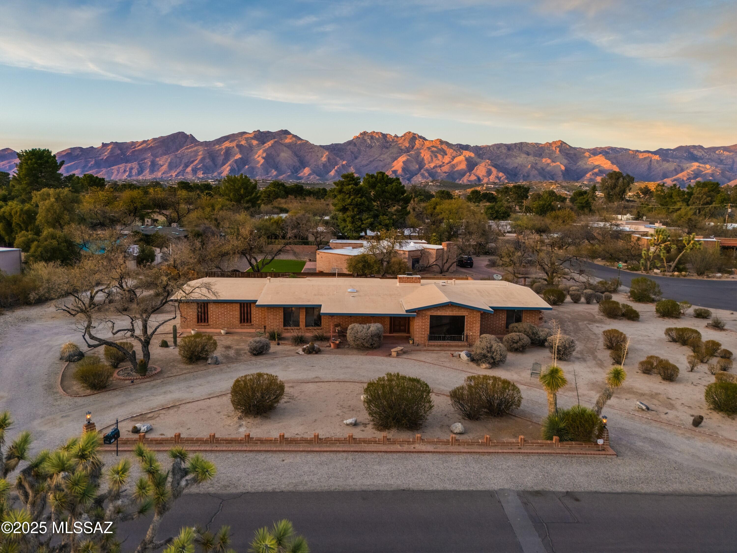 Charming Tucson Country Club Estates Home with Mountain Views. Discover timeless elegance in this classic burnt adobe home, perfectly situated on a spacious .55-acre corner lot in the highly sought-after Tucson Country Club Estates. From the inviting front porch to the architecturally pleasing details throughout, this Territorial-style residence exudes warmth and character.
Inside, you'll find neutral-toned concrete overlay floors, large picture windows that invite natural light, and a charming brick gas fireplace—the perfect spot to gather on cool desert evenings. The split floor plan offers flexibility with separate living areas, while the spacious kitchen nook is ideal for morning coffee or casual meals. This well-maintained home features several recent upgrades for peace of mind, including a new HVAC system (Dec 2020), and a new hot water heater (Dec 2021). Step outside to the north-facing backyard and take in the stunning view of the Catalina Mountains. There's ample space to add a pool and create your dream outdoor oasis. The Tucson Country Club Estates Community is known for its vibrant, welcoming atmosphere, with neighborhood picnics, parades, block parties, and scenic walking paths that make it more than just a place to liveit's a lifestyle. Best of all, this home is not part of an HOA. 

Don't miss your opportunity to own a piece of Tucson charm!