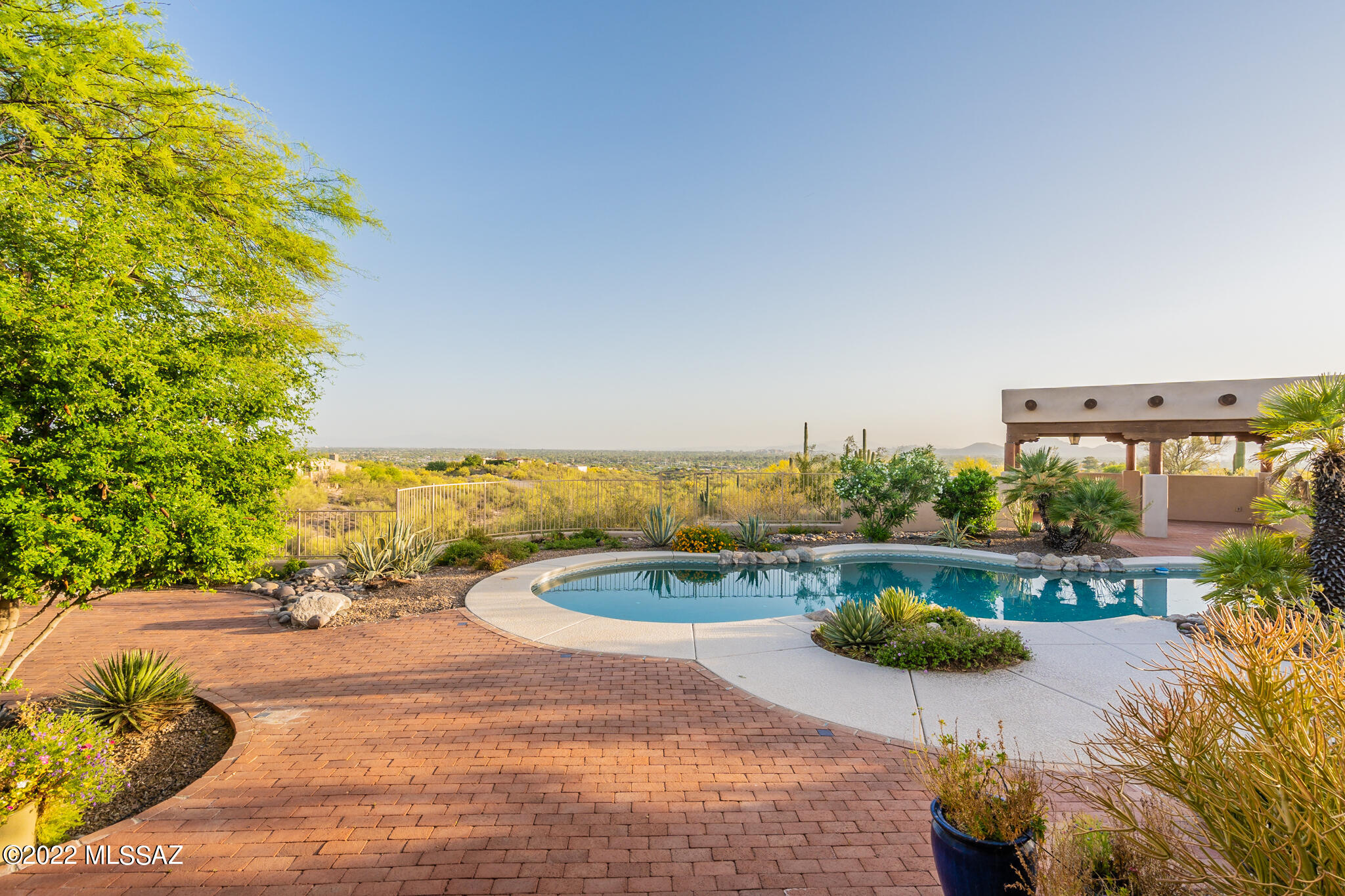 The epitome of Southwestern living can be experienced in this classic Santa Fe style home, showcasing a prime Foothills location. This exceptional 3BR/4BA/Den, masonry stucco home was built by longtime custom builder Mike Wachs on a 4.13 acre lot with unrivaled city and mountain views from just about every viewpoint in the home. As you make your way up the long, private driveway, you get a sense of the inviting location that was chosen for this home. 
Entering through the courtyard gate and entry door to the open foyer exposes hand crafted beams, Saltillo tile floor and custom cabinetry.  You will immediately notice the living room with its large gas fireplace and the incredible city views looking south. 
A superb chef's kitchen, with Sub Zero refrigerator/freezer, large island with gas cooktop, double ovens and a bar area with mini fridge make entertaining a breeze. The kitchen is flanked by a generous sized family room, breakfast nook and bonus area that can be utilized in many ways.  
The split bedroom plan allows the spacious Primary Suite to be in a world of its own.  Contained within this suite is the bedroom, sitting area with gas fireplace, private patio, exercise room and Primary bathroom.  The bathroom includes dual closets, dual vanity areas, a walk-in shower and jetted tub.
A beautiful den with an abundance of built-in cabinets and a gorgeous Catalina Mountain view sits outside of the Primary Suite.  The den is complimented by a full bath just across the hallway.
The guest wing includes a generous laundry room, as well as two bedrooms with en suite baths, one of which doubles as a pool bath.
The backyard is showcased with a Pebbletec pool, built in gas grill, ramada and a 180-degree Tucson city light view.
This fantastic property finishes up with an expansive 3 car garage containing a massive storage room and separate workshop.
Additional features include Pella windows and doors, built in vacuum and water filtration system.
This desert hacienda is a must see for anyone looking for the privacy of a large, foothills property, coupled with views that are rarely seen in tandem.