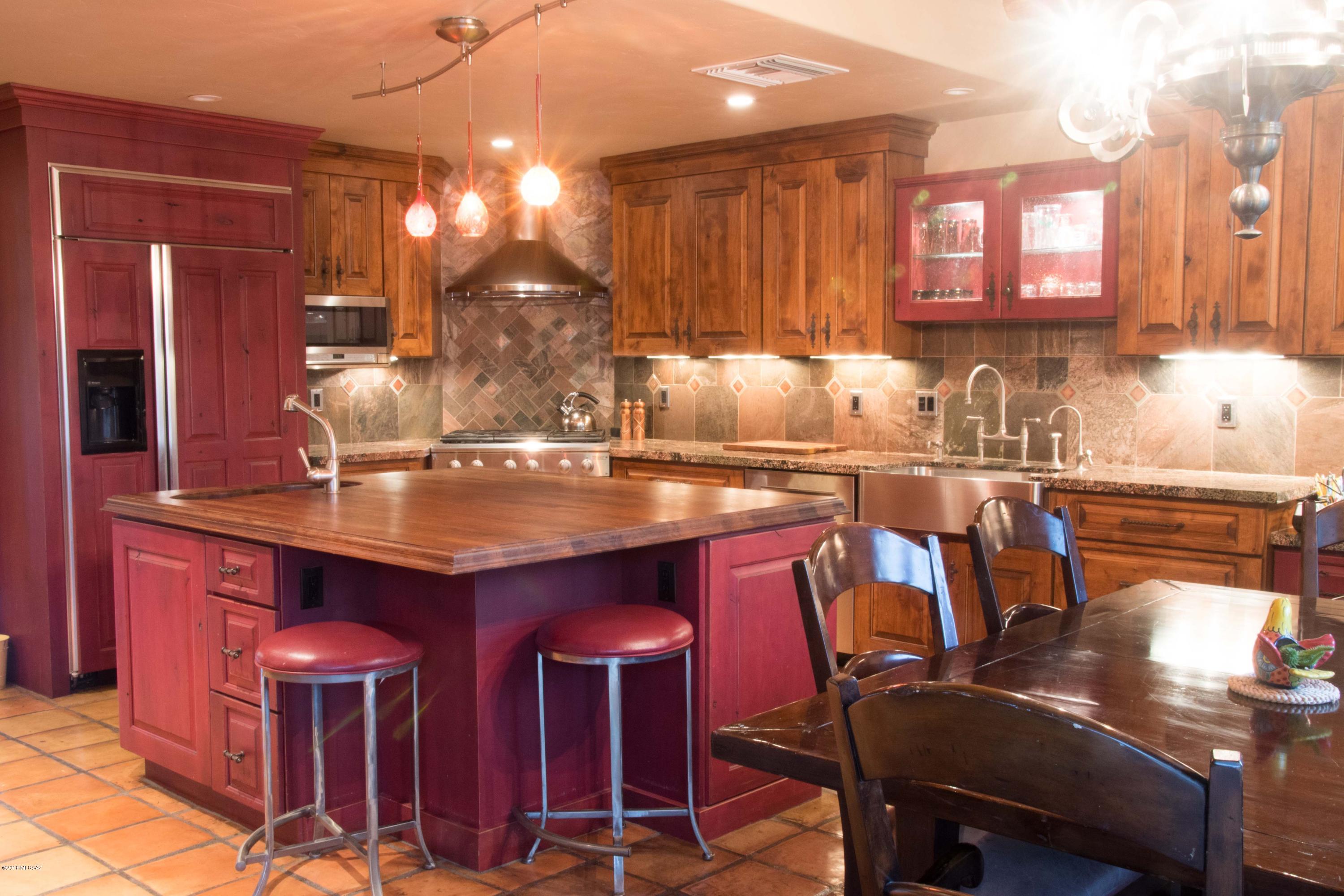Behind a private gate, down a long brick driveway you will find this Classic Santa Fe that combines Old World charm with modern architectural details. The kitchen includes granite and wood counters, knotty alder cabinetry with natural and cranberry stain with a backsplash tile of polished copper slate. The master bath is an elegant mini-spa clad in alternating swaths of rough and sleek sandstone with a private courtyard, complete with wall fountain visible through a floor-to-ceiling wall of glass. Enjoy the best of Tucson outdoor living from the charming entry courtyard and the back yard with verdant lawn, custom fencing, elevated dining area with desert and Catalina mountain vistas, outdoor kitchen, slide, waterfall and spa features, covered brick patio.