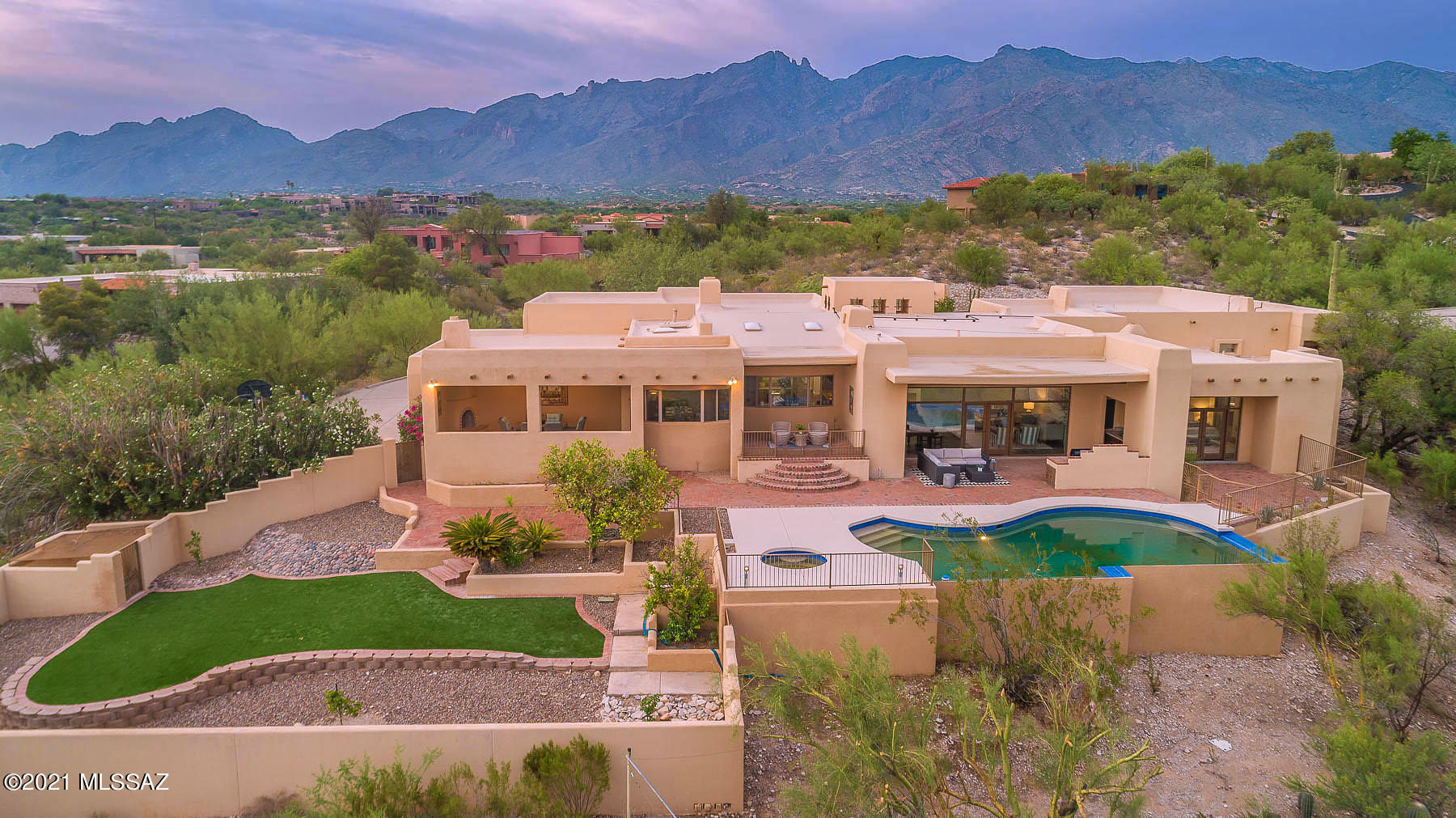 This private and inviting prior Southern Arizona Realtor Home Tour winner, situated on 1.83 Acres of prime homesite in guard-gated Catalina Foothills 10, has been updated with gorgeous new lighting fixtures, new fireplace surround, fixtures and landscaping. With over 5200SF, sweeping city & mountain views, fresh paint and handsome slate flooring throughout, five fireplaces, a stunning pool/spa and multiple patios and courtyards, this is the picture-perfect showcase of natural beauty in exclusive ''Cat 10''. There is generous space for intimate family gatherings and sumptuous entertaining, and many well-lit walls for fabulous displays of art for the collector. Featuring stunning slate floors and granite counters throughout, coffered and ribbed wood ceilings, and a contemporary palette with a none-the-less Southwestern flavor, this is an inviting home not often seen on the market. Enter through handsome iron gates into a brick-floored courtyard graced by a kiva fireplace, and on to the elegant leaded double doors into the atrium foyer and look across the sunken living room through walls of windows to the lovely pool and expansive vistas of welcome greenery and mountain ranges across the Tucson Valley. Heads up for sunsets! The graciously spacious dining room and adjacent family room share a magnificent four-way open stone fireplace and vistas of the Catalina Foothills and landmark Finger Rock. A private courtyard is accessible from the dining room. The equally well-sized kitchen and breakfast room provide vistas to the south and east of desert greenery and the many mountain ranges across the Tucson Valley. In the kitchen, enjoy cooking with the many granite counters, new sink fixture, two dishwashers, large island for gathering and serving, wine refrigerator, five-burner gas cooktop, wall ovens and desk area. Access a private patio above the pool from the kitchen, and from the breakfast area step out to a charming outdoor dining area with another delightful fireplace for our chilly desert nights, overlooking the gardens and large turf area of the rear yard. There is a cozy den/office, three guest or children's bedrooms, a stunning large guest bath, and a spacious owner's suite with a kiva fireplace and glass doors out to a privately gated patio, more vistas of mountains and city lights, and easy access to the pool/spa. The adjacent handsome owners' double bathrooms are connected by a large walk-through double shower showcasing granite walls and benches. A substantial walk-in closet area features another leaded glass window, providing light yet maintaining privacy. Perfectly located in the heart of Tucson's famed Foothills, with access to the sought-after District 16 School District and Catalina Hills High School and near Tucson's best shopping and dining experiences, with an easy commute to downtown Tucson, this home awaits your visit. Enjoy the creative staging provided by Julie Lee and Desert Sky Design.