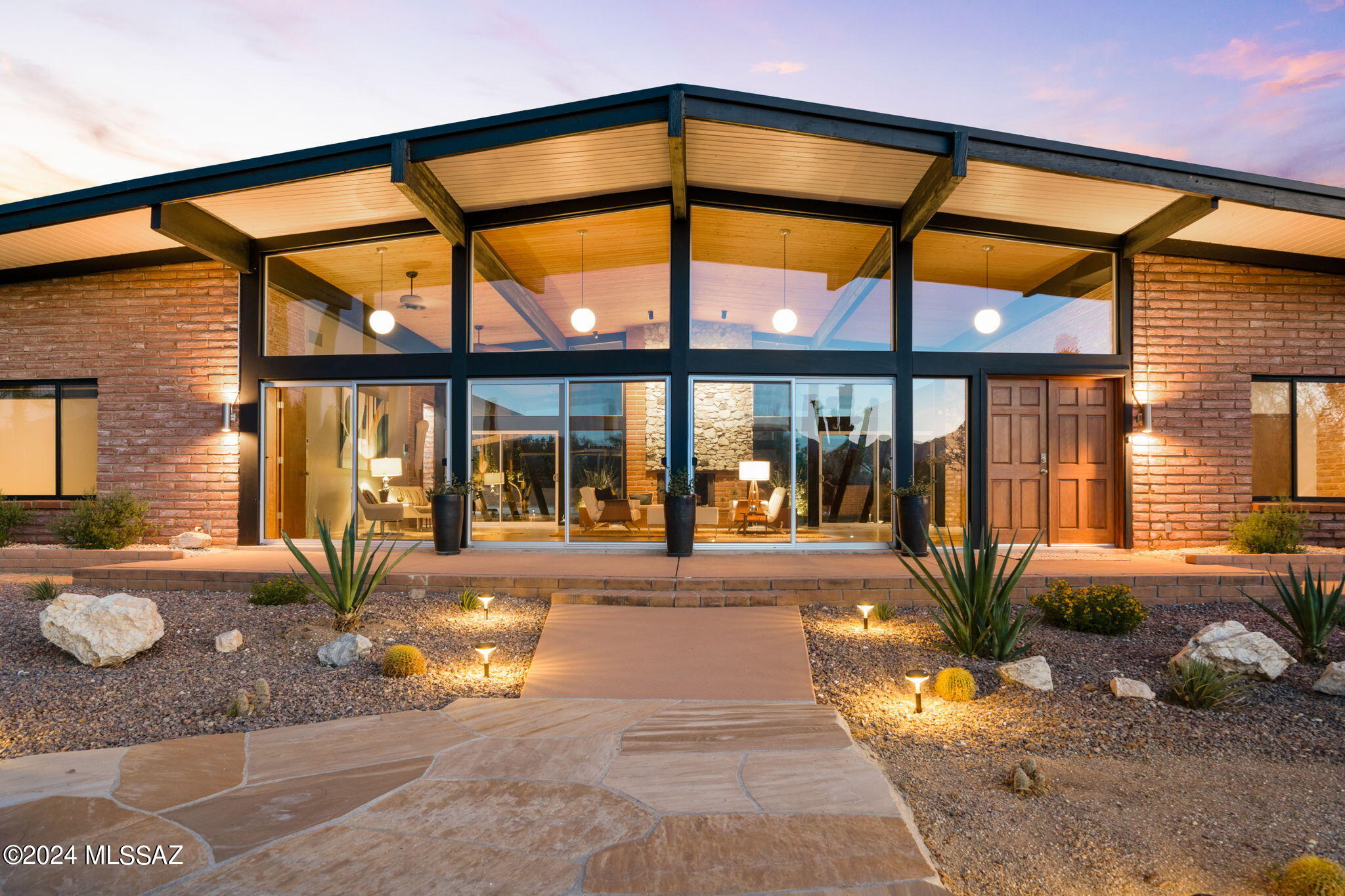 Welcome to this exquisitely revitalized Mid Century Modern masterpiece, a true architectural treasure in the iconic Frank Lloyd Wright style.  Designed by renowned architect, Floyd L. Cullop, and built in 1967, it is nestled on a sprawling 3.33 acre lot.  The home offers direct access to the captivating Saguaro National Monument East, which is just blocks away.  This remarkable, absolutely one of a kind property harmonizes classic design with modern luxury, encapsulating the essence of Tucson's distinctive architecture.  This iconic architectural gem features original burnt Adobe brick post-and-beam construction throughout,  Located in the highly sought after community of ''The Notch'', the property presents breathtaking panoramic mountain views. Where nature's beauty unfolds in every direction, offering spectacular sunsets and the serene presence of over 100 majestic saguaros gracing the landscape.  Inside, the home boasts 5 elegantly appointed bedrooms, each designed to provide comfort and tranquility.
The 3 completely remodeled and upgraded bathrooms are a testament to  modern craftsmanship, featuring high-end fixtures and finishes that seamless marry style and function. For ultimate relaxation, enjoy the infrared sauna, tucked away in the primary bathroom, a spa-like retreat right at home.  The interior celebrates Mid Century Modern aesthetics with a flair, highlighted by soaring ceilings in the expansive 1,100 sq. ft. great room.   The dramatic natural stone gas fireplace serves as a stunning focal point, inviting warmth and ambiance to gatherings, intimate family moments and holidays.  The kitchen is a culinary enthusiast's dream, showcasing extraordinary walnut cabinetry in true Mid Century style, equipped with state-of-the-art KitchenAid appliances, including double ovens, 36" cooktop, sleek dishwasher, counter-depth refrigerator, as well as  a 140 bottle dual-zone wine refrigerator, striking quartz countertops that shimmer with elegance.  This home is outfitted with all new dual-pane windows and doors, ensuring energy efficiency while allowing natural light to flood the living spaces.  The entire property has undergone a complete electrical upgrade, featuring a new 400-amp panel, enhancing the home's functionality.  Additionally, a brand-new multi-zone heating and air conditioning system ensures year-round comfort.  All floors were refinished with a classic cement for ease in cleaning.  New garage doors were added as well a a brand new driveway.
The professionally designed backyard is an entertainer's paradise, with lush Patriot turf, a custom 12x18' steel pergola that provides the perfect shaded retreat, and new irrigation systems paired with outdoor landscape lighting.  At the heart of the outdoor oasis is a fully renovated pool and deck, complemented by new pool equipment, inviting you to indulge in refreshing swims under the warm Arizona sun.  This home is not just a place to live, it is a masterful blend of design, comfort, and nature, offering an unparalleled lifestyle that truly represents the pinnacle of modern living in Tucson.