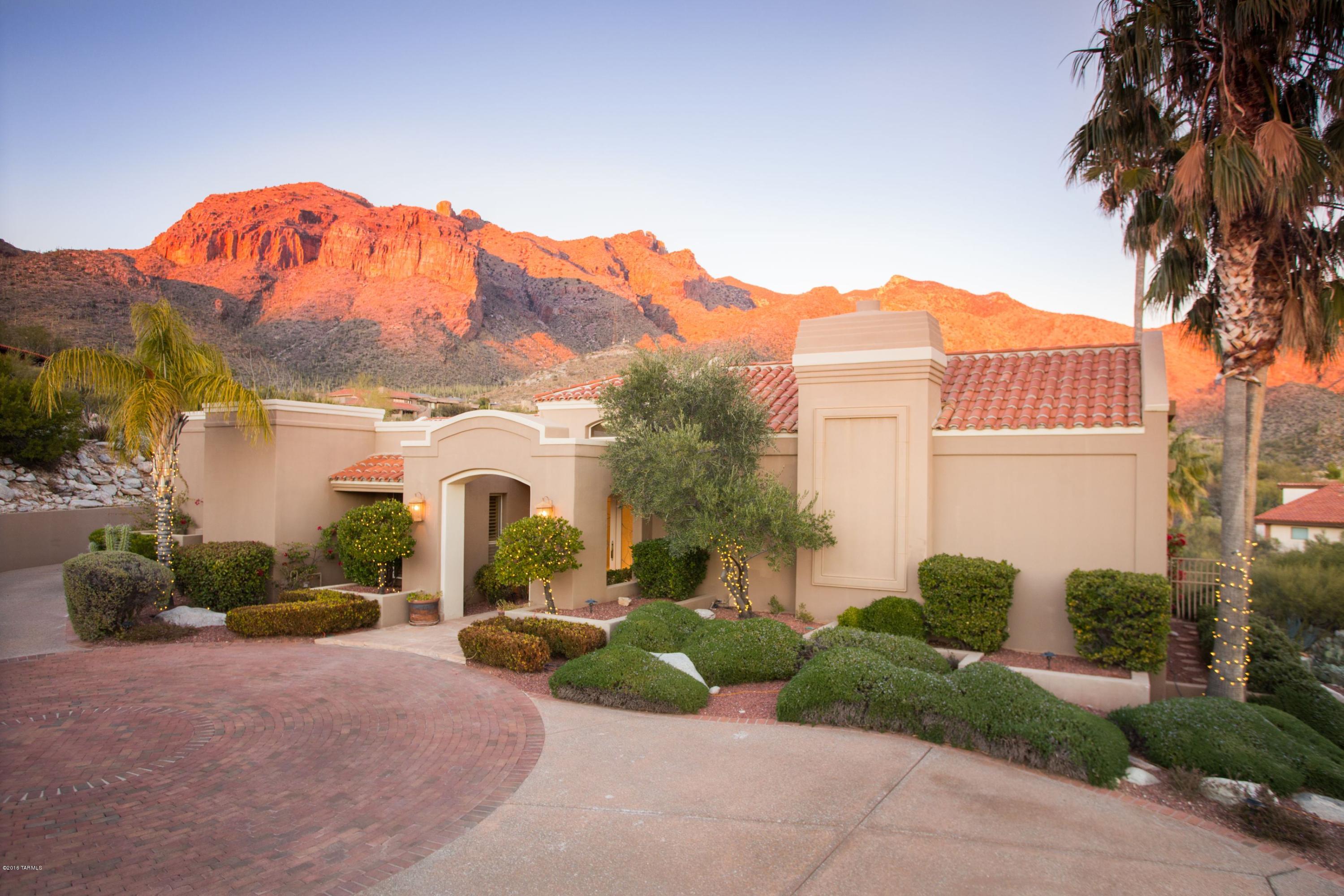 NO STEPS - Gorgeous home in exclusive guard-gated Cobblestone sits high above Tucson with dramatic mountain views and city lights that go on and on. This home offers elegant & casual living. Beautiful outdoor living with negative edge pool overlooking the City. An spectacular entry foyer leads you to an elegant living room and formal dining to a gourmet eat-in kitchen w Quartzite countertops. Large, cozy family room with fireplace and wet bar. Split master suite with HIS AND HER BATHROOMS & CLOSETS with door leading to spa. Master Suite has private den/library w fireplace and a mirrored exercise studio with bath, wet bar & sauna w/courtyard. Three guest bedrooms,2 w in-suite ba. Brand new pool heater
