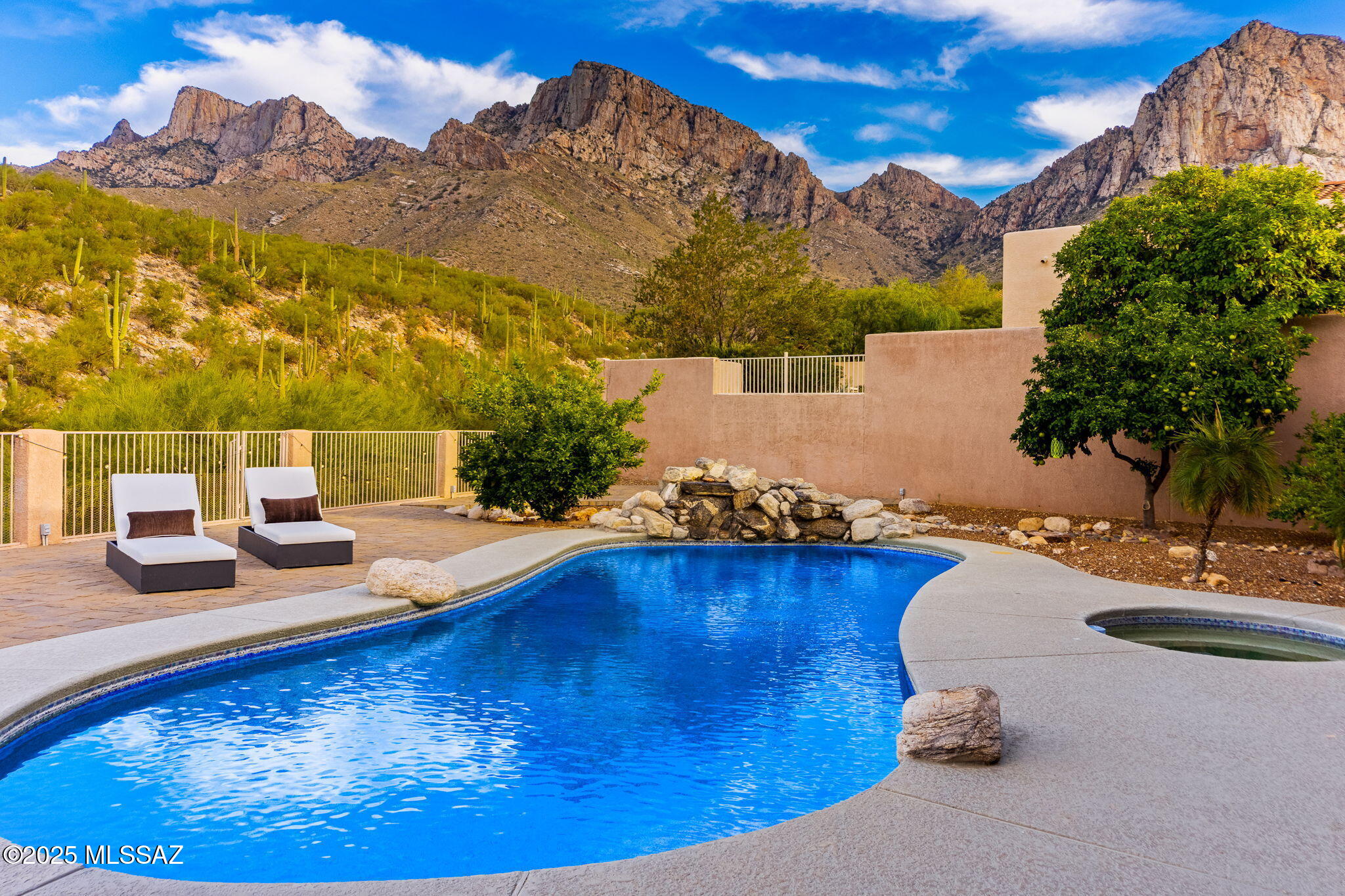 VIEWS! If you've been looking for one of the best mountain views in Oro Valley, this is it! Discover refined living in this thoughtfully updated 4-bedroom, 5-bathroom contemporary home, nestled within the 24-hour guard gated La Reserve community. Spanning 3,300 square feet across two stories, with the primary bedroom DOWNSTAIRS. 

Step inside to an open great room featuring a gas fireplace seamlessly flowing into a formal dining area and a versatile den/bar with a beverage refrigerator and ice maker. The remodeled kitchen is a culinary haven, boasting custom cabinetry, quartzite countertops, a spacious island with breakfast bar, and premium stainless-steel appliances including a 6-burner gas range, and custom tiled backsplash. 

The primary suite on the downstairs level offers a serene retreat with unobstructed mountain views of Pusch Ridge, complete with its own entrance to the backyard. The showstopper is the newly renovated master bath that makes you feel like you're at the spa featuring a relaxing soaking tub, a separate spacious walk-in tiled shower, dual floating vanities, and 2 LED mirrors. Also downstairs, is a functional office or exercise room. Upstairs, 3 additional bedrooms and 3 additional bathrooms provide privacy. 

Outside, embrace desert serenity with panoramic views of Pusch Ridge and the Catalina Mountains. The low-maintenance backyard oasis includes a sparkling pebble-tec pool with waterfall, spa, outdoor kitchen with BBQ grill, sink, and refrigerator, plus a cozy fire-pit for year-round enjoyment. The spacious backyard also has several mature citrus trees including grapefruit and orange tree. 

Additional recent enhancements like new windows, doors, HVAC systems, re-piped water lines, and irrigation ensure modern efficiency. Finishing off the home is a 3 car garage with ample storage. Located in Oro Valley with easy access to top rated golf, shopping, and restaurants, this home offers a perfect balance of luxury and tranquility.