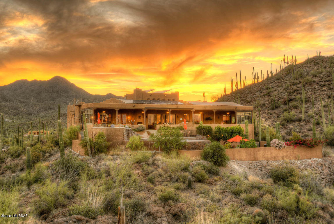 Gorgeous custom built home looking over Tucson with spectacular panoramic views! Nestled in the Saguaro studded hills, this property sits on 4.97 acres and borders the 880 acre Sweetwater Preserve. The sunset views are breathtaking! Walking into the home you'll notice the detail that has gone into the design of this luxurious estate. Features smooth concrete flooring, cathedral ceilings, and a large great room! The kitchen features beautiful granite countertops, stainless steel appliances, a wrap around breakfast bar, large island, & much more! The covered patio has some of the best views of the city lights at night w/ a cozy beehive fireplace for the cool desert nights. Gated entrance to the property. Come and see all this one of a kind property has to offer in person!