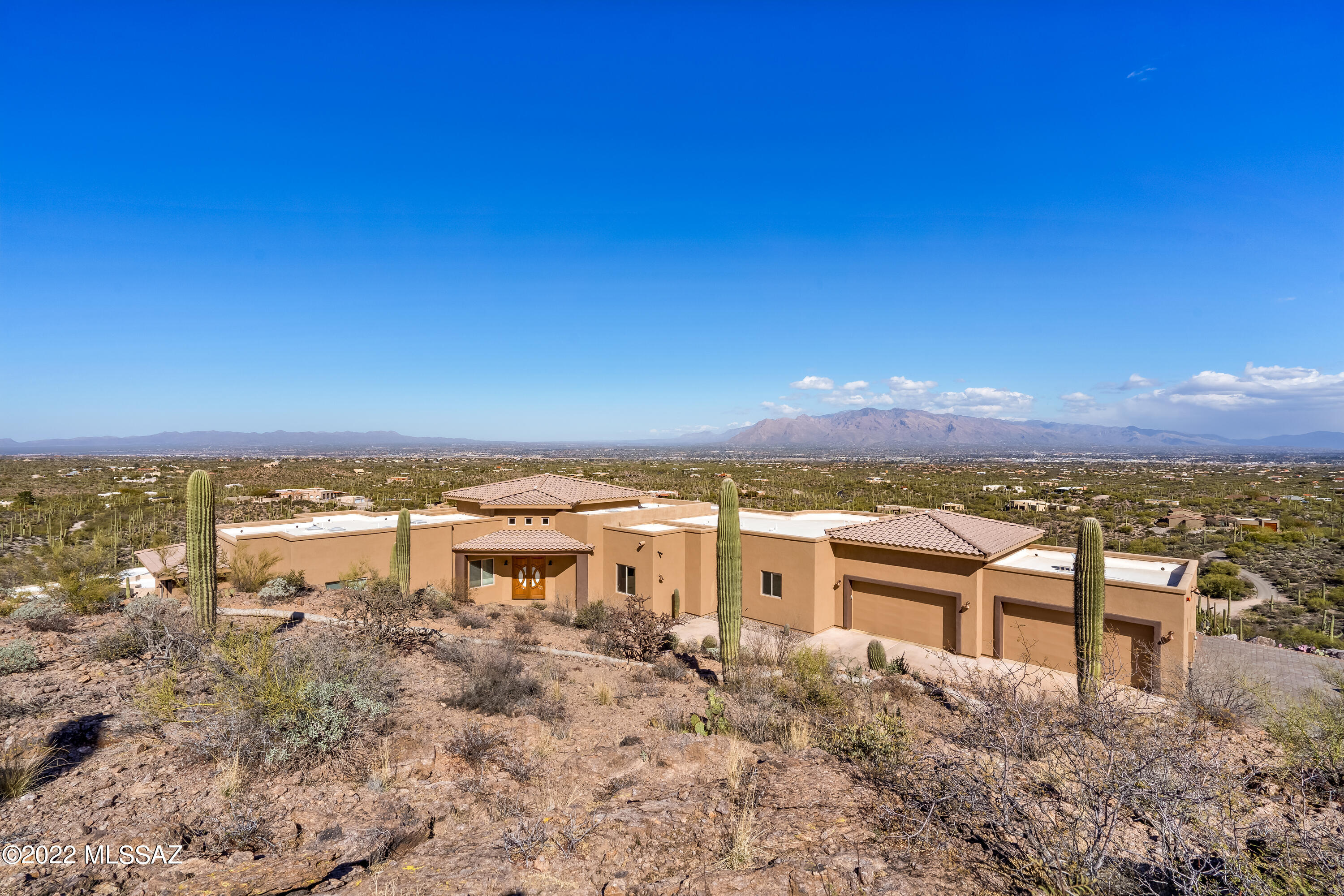 Stunning one of a kind home resting high on a hilltop with limitless views of Tucson's city lights, saguaro studded Catalinas, Rincons, Mount Lemmon, Sombrero Peak and the valley's gorgeous sunrises & sunsets. Completed in April 2018 the home boasts 5 bedrooms, four of them are suites, 6600 sq. ft. under the roof with 3750 sq. ft. of living space. Entertainers dream with ample room on the east facing porch for gatherings large or intimate. Lounge in the PebbleTec pool or relax in the 6 seat modern spa. Tucked between the home and the mountain is a private seating area with a calming water feature. Paved road all the way to the private gate at the entrance to the property, plenty of parking on the brick paver driveway and a 4 car garage with wifi equipped garage doors and room to park an RV behind the garage. The chef's kitchen includes a 36 inch burner, built-in refrigerator, double ovens and a special order dishwasher. Three fireplaces located in the living room, dining area and owner's bedroom. The owners suite boasts a floor to ceiling travertine shower, luxurious walk-in closet, dual vanities and views of the sparkling city lights. Guest quarters with a kitchenette, private bath and separate entrance is perfect for guests. Accompaniments include porcelain tile throughout, travertine stone in the baths, upgraded carpet in the bedrooms, walls of windows, alder & mahogany doors, central vacuum, built in surround system with 4 front & 4 back speakers, 4k industrial surveillance cameras with 230 ft range of night vision. Data connections throughout the home including the garage. Make an appointment for your own private tour of this mountain top home.