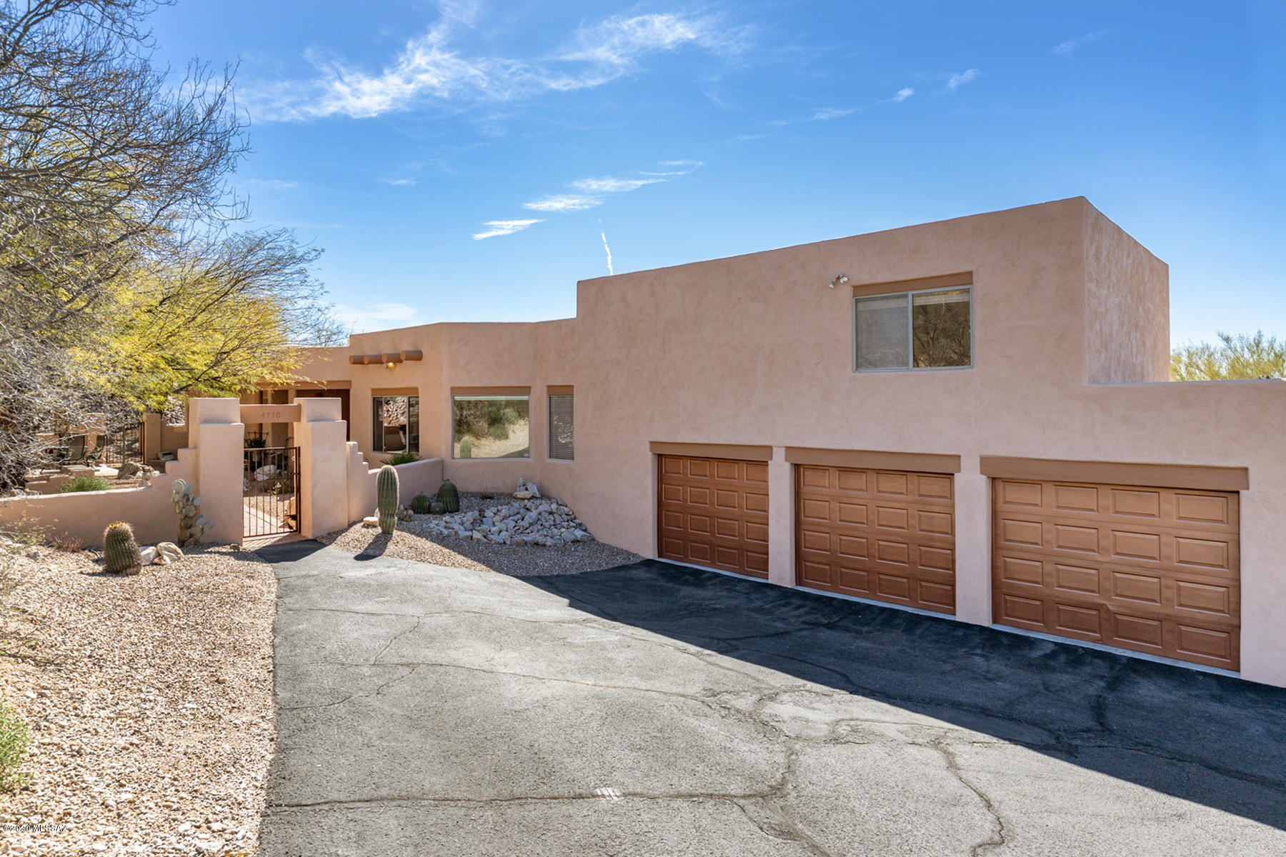 A Spectacular lush gated courtyard boasting Catalina Mtn views, flagstone decking & tranquil fountain greets your guests upon arrival. This charming Santa Fe offers dramatic high ceilings, an abundance of skylights/walls of windows & french doors to keep spaces light-filled & open & bring the views in. Rooms flow seamlessly together through vigas & arched entries. 2 fireplace's enhance the fmly rm & mstr suite. A perfect floorplan offers the main living, mstr suite, lrg bdrm & full bathrm on main floor & teen wing w/3 bedrooms & full bathroom privately situated upstairs. The center island kitchen features stainless appliances, wrap around breakfast bar, bayed eating area & plenty of prep space & storage. The resort-style rear yard features a pebble tec pool w/waterfall, fire pit, ++