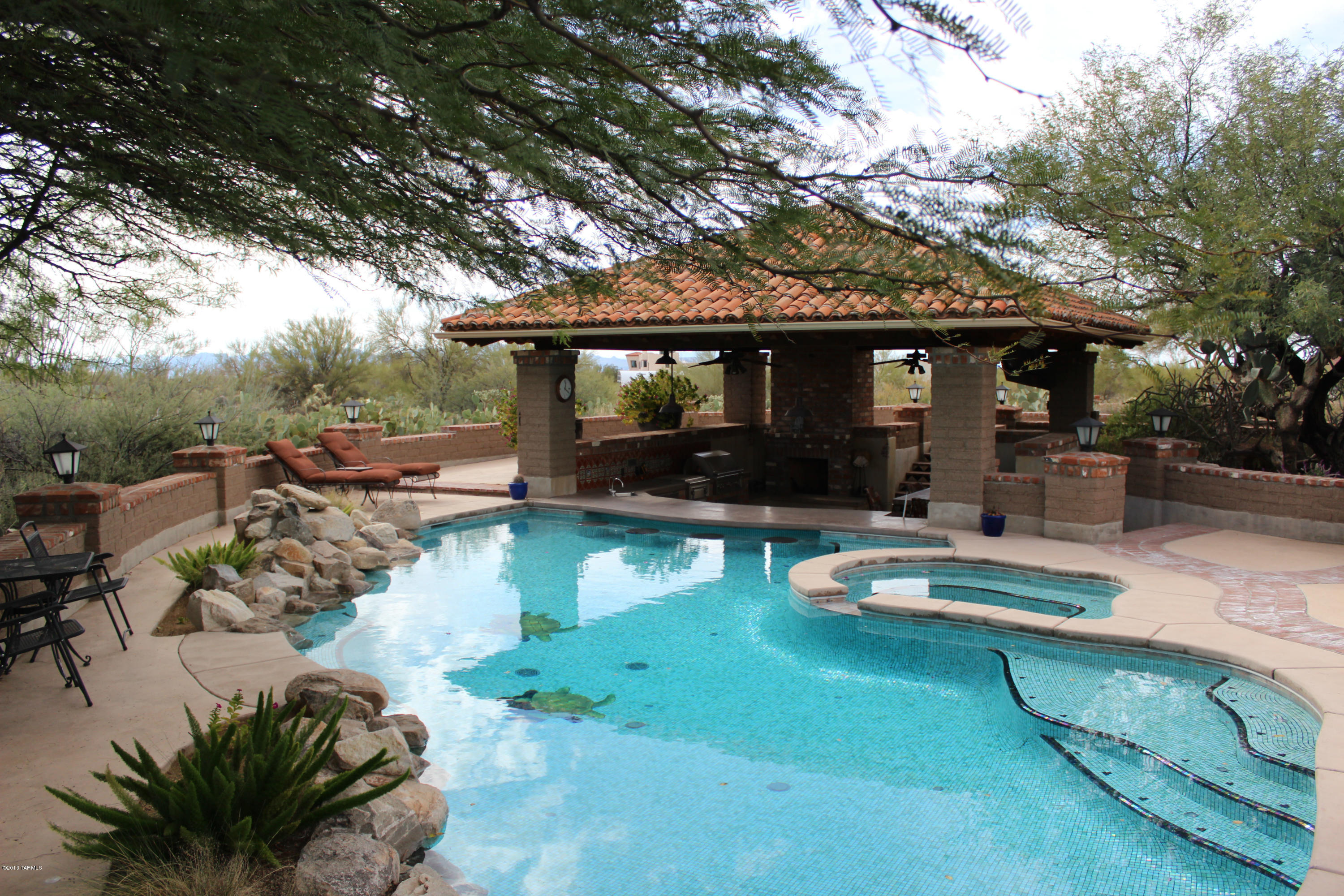 A True Tucson Spanish Hacienda w/Amazing Mountain Views located in  Prestigious La Cholla Airpark. Surrounded by 7.93 Acres of Natural Desert brings a Quiet,Peaceful & Private Lifestyle.Arrive at your 4376 Sq Ft Custom Built w/16-24” Mud Adobe Home thru your private gated entrance. Custom Details thru out home include: Custom Douglas Fir Doors, Mesquite Cabinetry, Ocotillo Closet Doors, Vaulted Ceilings w/Wooden Beams,5 Fireplaces.Stunning Outdoor includes a unique Mosaic Pool w/swim up bar stools,Outdoor kitchen w/custom Lynx BBQ,Ramada,TV w/Surround Sound,Outdoor Balcony for extraordinary Mtn Views & Guest Bath Facilities that will make you feel like you are at a Resort.For Automobile Enthusiast 6 Car facility includes 2 completely separate 1,000sq garage/workshops-cooled & so much mor