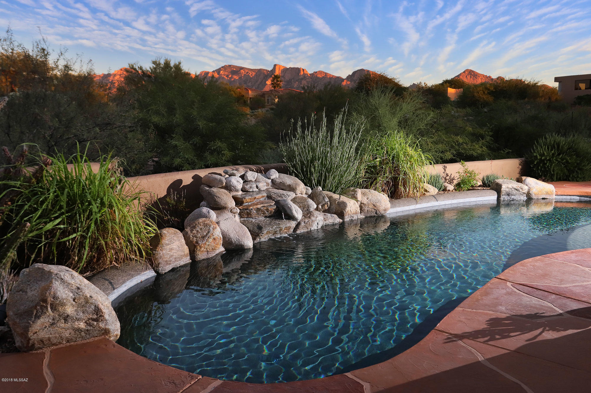 Seller shall entertain and/or counter offers between $795,000-$825,000. A living experience in the Oro Valley Area blending Indoor and Outdoor Living Spaces with a seamless design that let's the natural lure of Coyote Ridge embrace you as you enter this luxurious gated community, populated by custom homes with unsurpassed quality and design. This custom home reflects soft contemporary southwest architecture and is privately positioned on a 1-acre premier site  with amazing Pusch Ridge views. A private drive leads to a beautiful 3,859 Sq Ft custom home that features 3 bedrooms, 2.5 baths, access to the over-sized 3-car garage with skylights and epoxy flooring and secondary bedrooms that link to a Jack / Jill bathroom with travertine counter tops and Jacuzzi tub. Attention to detail embodies every space, nook and crevice. A culinary inspired  kitchen, equipped with stainless steel appliances, granite counter tops, knotty alder distressed cabinetry, walk-in pantry, 5-burner gas cook top, and a huge prep island with breakfast bar and built-in vegetable sink. A perfect set up to prepare family meals or for entertaining on a larger scale. The kitchen flows perfectly into the formal dining room where you have unobstructed views of the Catalina mountains and circulates to the expansive great room that features 14' ceilings, 8' knotty alder doors, a floor-to-ceiling gas log fireplace accented with flagstone, lighted display shelving, and sealed travertine tile throughout. Just off the great room is an entertainment media/theater room with surround sound where you can relax and enjoy a theater-like experience right in the comfort of your own home. Grand double entry doors lead you to the superb master suite that includes a full-scale walk-in closet, soaring ceilings, a spa-like master bath with executive height vanity with 2 custom sinks set in travertine, an oversized jetted tub, large walk-in shower with multiple shower heads, and French glass double doors that lead to the covered veranda + pebble tech pool.  The Tucson lifestyle shines in outdoor living, bringing paradise to the external areas of your home, as well. An ideal east facing backyard oasis with the most spectacular mountain views in the area, letting you witness the reflection of the colors of ancient sunsets, right before your eyes. From the fine quality of construction and well thought out floor plan, your expectations can be easily met!