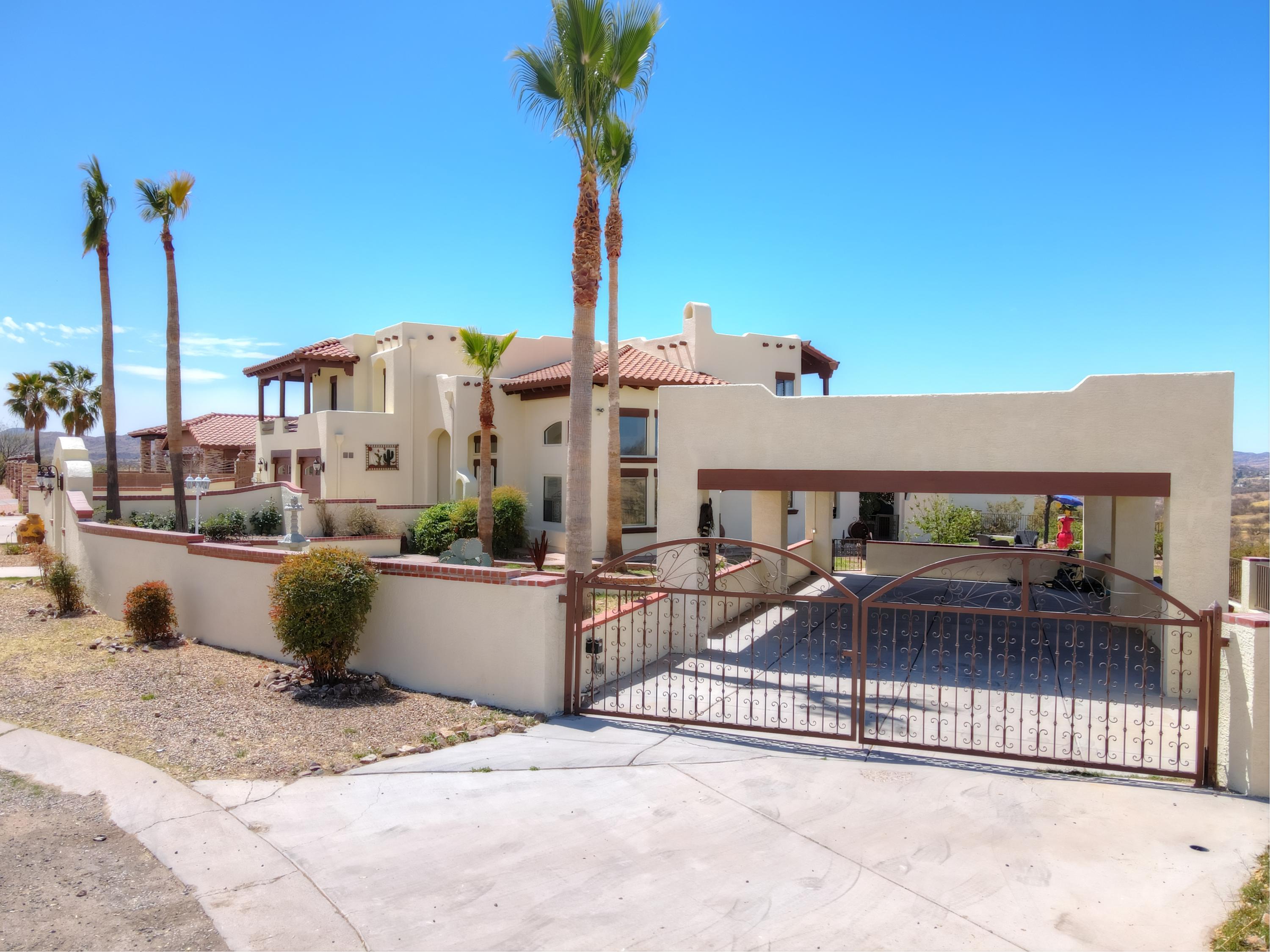 Located in a cul-de-sac in Indian Hills, this custom built 4BD 4BA two-story home is a must see. Beautiful entrance with iron wrought gate and cantera stone fountain. Flowering vines surround the Spanish style facade. On the main floor there are vaulted ceilings throughout, laminate flooring and an open concept living area. The kitchen has mesquite cabinetry, bar stool seating, and is elevated by a 4-foot chandelier. Also on the main floor is a second dining area, a bar, an office,  full bath and a  great room w view. The stairs have custom railing and natural wood finishes. The master bedroom has a private deck and an ensuite with a jacuzzi tub. The master is connected to another room used for an office or may be converted to a grand closet. This home features 2 balconies panoramic views In the backyard there is a kiosk, built-in grill area with chimney, and a fire pit perfect for entertaining. The panoramic view from this home is spectacular! You get to see both neighboring countries, the US and Mexico. Guest House is separate from the home and is 255sqft with an upgraded bathroom. Below the Guest house there is a storage room that is also 255sqft. Attached 2 car garage and additional car port for up to 4 vehicles or a boat , lake patagonia is only 12 miles away. The landscape features a rose garden, palm trees, a cherry blossom tree, nectarine tree, palo cacti, and flower beds.