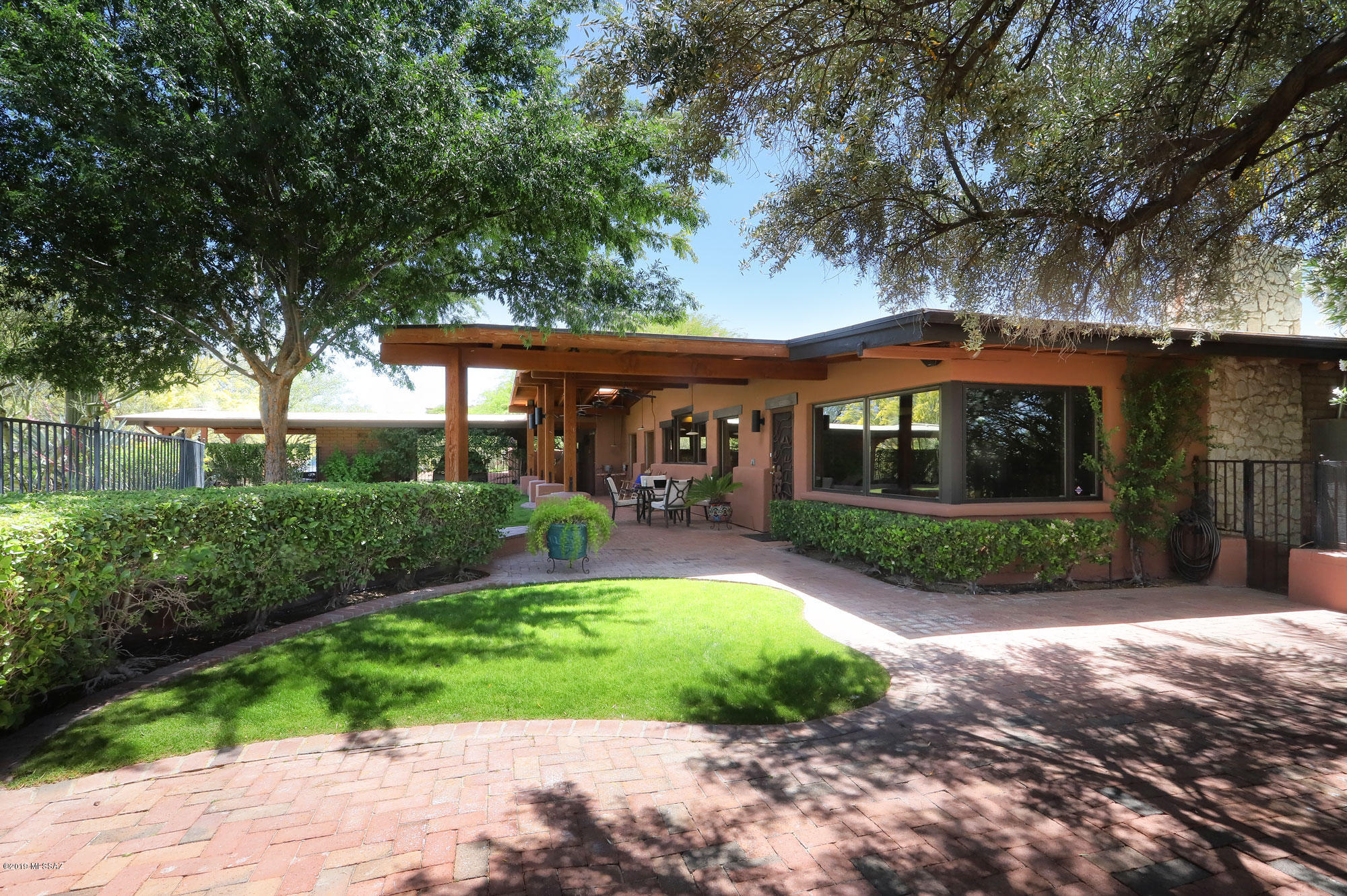 Enter into the magical courtyard of this incredible Mid-Century David Fraker built home. Open the front door to the 40'x25' great room/dining room w/high tongue & groove ceilings & incredible grandeur in the totally flexible space w/stone accent wall. Kitchen/breakfast/family room area w/professional 6 burner gas range, quartz countertops & dramatic mountain views. Family room w/beamed & planked ceiling & beehive FP. Pass through the 15'x15' study to enter the updated master retreat w/FP, remodeled bath & walk-in closet. All bedrooms have en suite bath. Laundry room is large enough for a hobby area. 2 separate yards: the north has a covered patio, FP, lush vegetation & the south has a pool, covered patio & city views. Main house is overshadowed by the cuteness of the 2 addl guesthouses.