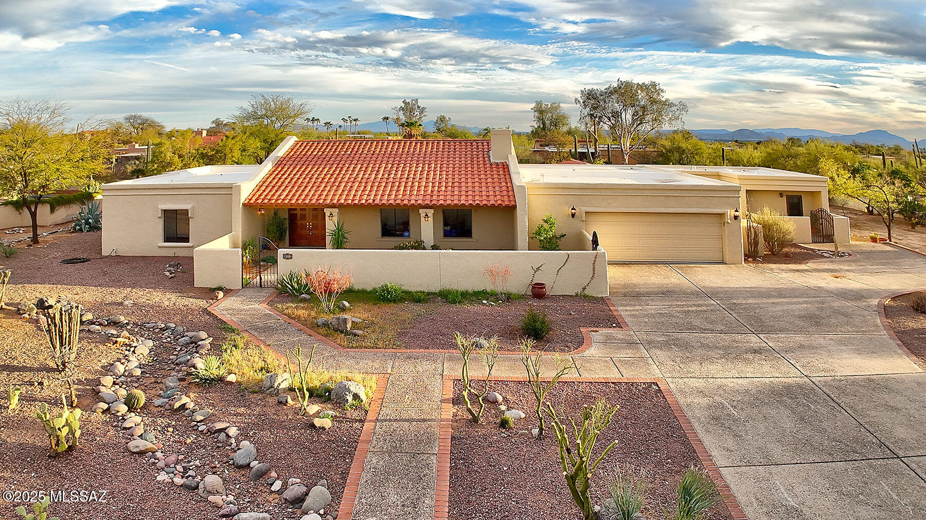 Located in the desirable Shadow Hills neighborhood of Catalina Foothills, this exceptional home offers 2,642 sq. ft. of living space with 3 bedrooms and 2.5 bathrooms in the main residence. Vaulted ceilings create a grand entrance, leading to a spacious living and dining area and wall of windows framing the back yard. Elegant wood-like porcelain tile flooring extends throughout, while expansive windows flood the home with natural light. Three distinct living areas include a dedicated study/library with a fireplace, a separate family room, and a generous main living space. The primary bedroom includes an ensuite full bathroom & walk-in closet. The private, walled backyard features a covered patio and a large pool an ideal retreat for relaxation and entertaining. A separate guest house provides a perfect space for visitors or a mother-in-law suite.  Situated on a secluded lot at the end of a cul-de-sac, this property offers both privacy and breathtaking mountain views. Additional features include a two-car garage and off-street parking.