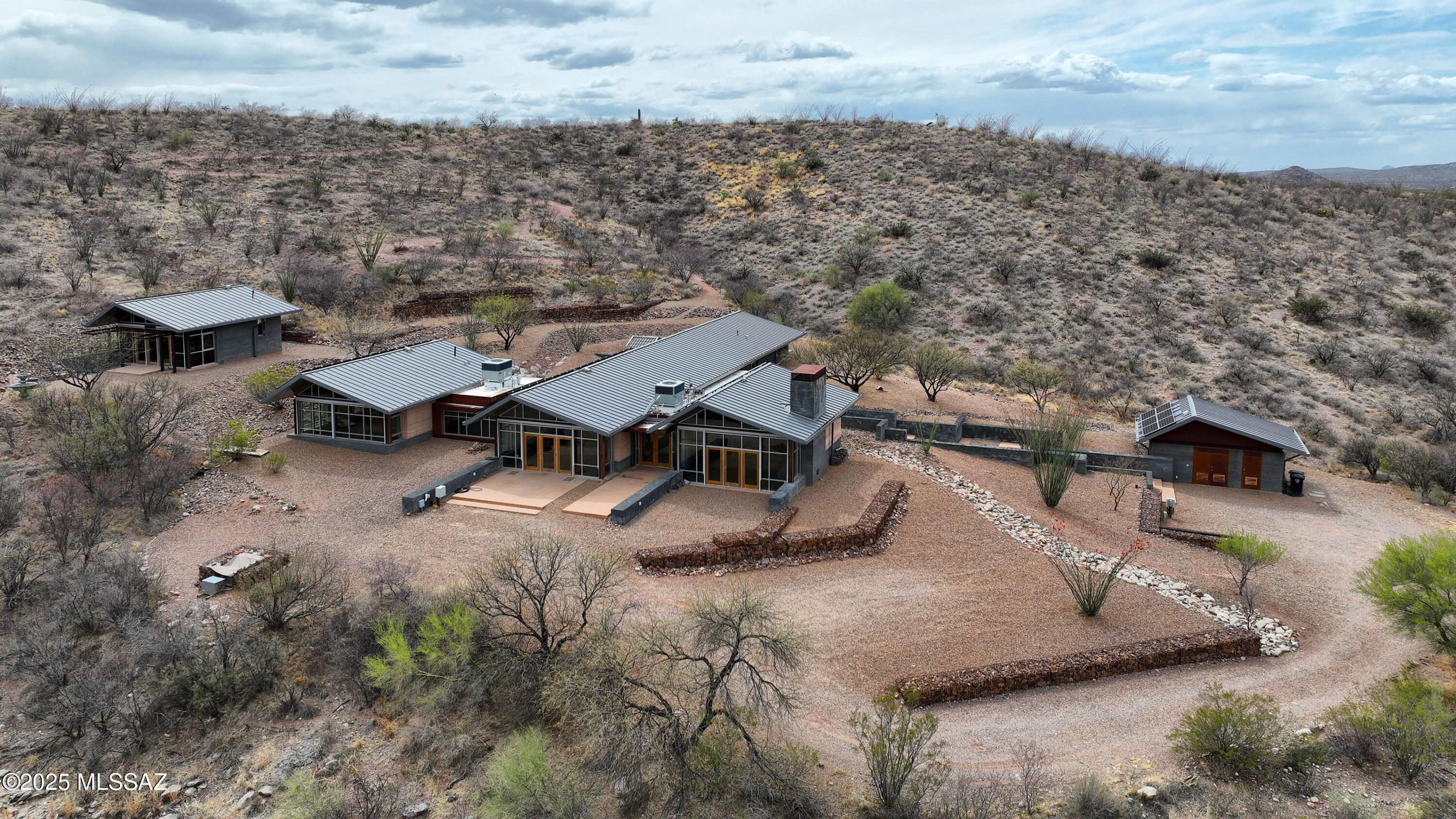 Welcome to this one of a kind compound on over 47 private acres w/spectacular views. Built to last with rammed earth & lava-crete construction designed for thermal mass w/commercial windows & doors, this home features beamed ceilings, metal roofs, underground wine cellar & a 1-mi. walking trail on the land. Spacious living area w/walls of windows framing the views, striking FP, modern kitchen w/lg island, breakfast bar & sizable dining area.  Concrete flrs thruout. Primary Suite w/more views & ensuite bath. Gst Qtrs connects by a lg covered breezeway & features 2 bdrms & full bath.  Terrific outdoor sauna.  Detached studio w/half bath ideal for ofc/gym. Located in the gated X9 Ranch commty, it's the perfect place to get away from it all & immerse yourself in the beautiful Sonoran Desert.