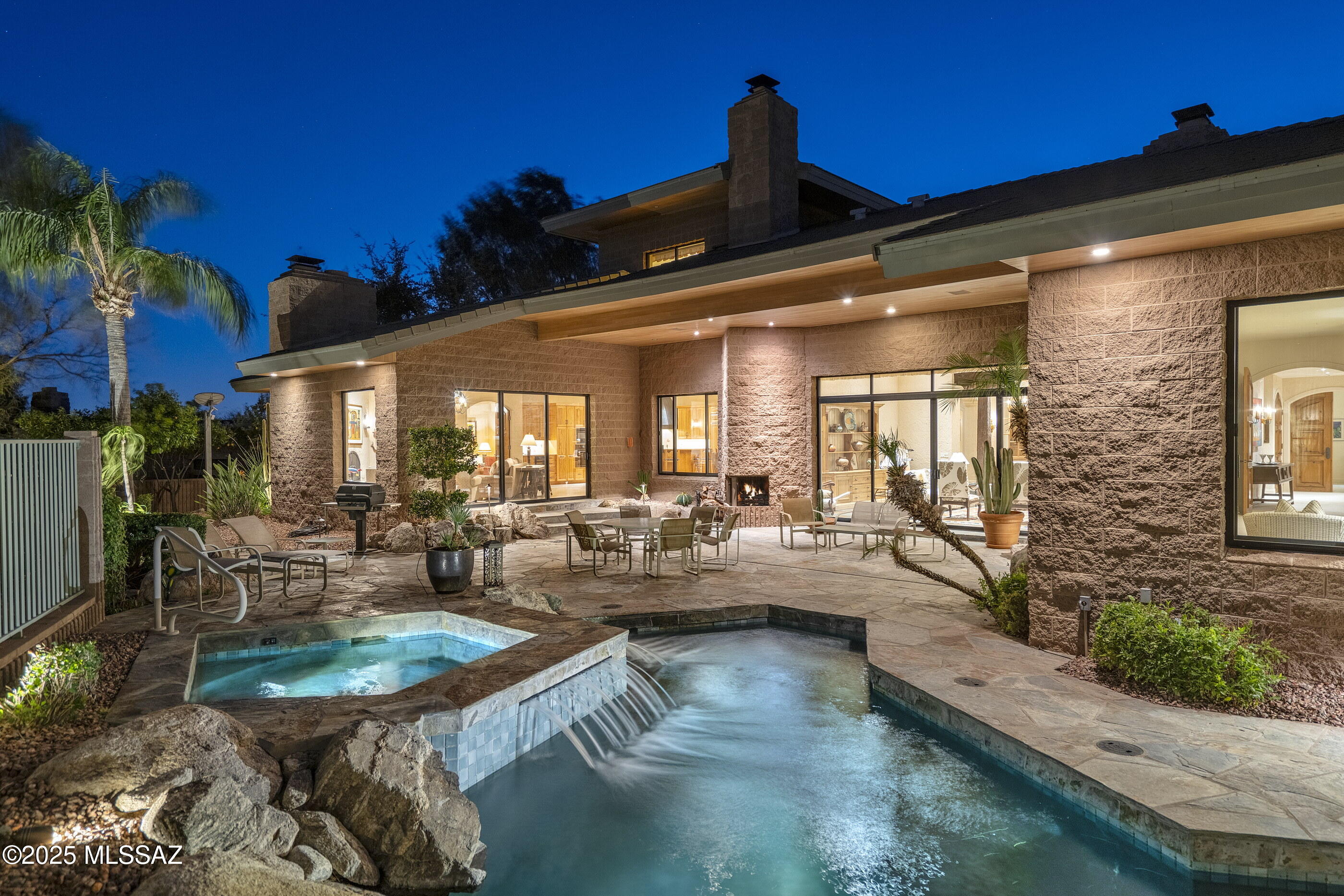 Located within the guard-gated community of Ventana Country Club, this residence is nestled at the base of the Santa Catalina Mountains, quietly integrated into the surrounding desert topography, while taking in views of the lush greens along the scenic Par 5 second hole of the Canyon course. The home occupies a generous lot, offering a calm and expansive vantage over the curated and desert landscapes, with distant mountain vistas framing the backdrop of this estate property. Crafted with enduring quality, the home is constructed from solid masonry using distinctive split-faced ''Ventana Block,'' a hallmark of timeless design and structural integrity. The entry sequence unfolds through a welcoming courtyard, where a natural rock water feature serves as a soothing focal point, setting the tone before stepping inside.The interior layout is composed of a series of interconnected living spaces, designed to accommodate both social gatherings and private moments. Upon entry, a high-ceilinged foyer introduces a series of rooms that are well considered in scale and proportion. Floor to ceiling windows in the main living area bring in natural light and open views, establishing a strong relationship between interior space and the surrounding environment.

Thoughtfully arranged for both form and function, the kitchen features a central island, custom cabinetry, and expansive surface space ideal for both prepping and cooking. Its functional layout provides a well designed foundation that promotes a natural sense of flow and everyday flexibility. With an orientation that naturally connects the kitchen to the adjacent dining and casual living areas, the space invites daily comfort as well as effortless entertaining. This cohesive arrangement not only supports lifestyle, but also leaves room for homeowners to infuse the space with their own personal touches, whether through design updates, curated treatments, or accents that reflect individual taste and style.

The primary suite is situated on the North end of the residence, oriented to maximize privacy and views. It includes two en-suite owner bathrooms and is supported by an oversized walk-in closet. Two secondary bedrooms nearby, offer flexibility depending on individual needs, with two additional bedrooms, located on the upper wing of the residence. 

Outdoor living spaces are well integrated into the overall plan, with a covered terrace that runs along the rear façade. The pool and spa are gently set into the landscape, with a water feature creating an informal gathering space where mountain and golf course views serve as a constant backdrop. Expansive flagstone flooring extends across the outdoor areas, defining multiple seating vignettes perfect for relaxing or entertaining. Designed with low-maintenance ease in mind, the exterior environment is ideally suited for both full-time residents and those seeking a lock-and-leave second home lifestyle.

Ventana Country Club is a long-established residential country club community located in the Catalina Foothills, offering proximity to private golf, tennis, state of the art workout facilities, desert trails, and amenities. This community offers a private, quiet setting, with a balance of natural surroundings and access to everyday conveniences.