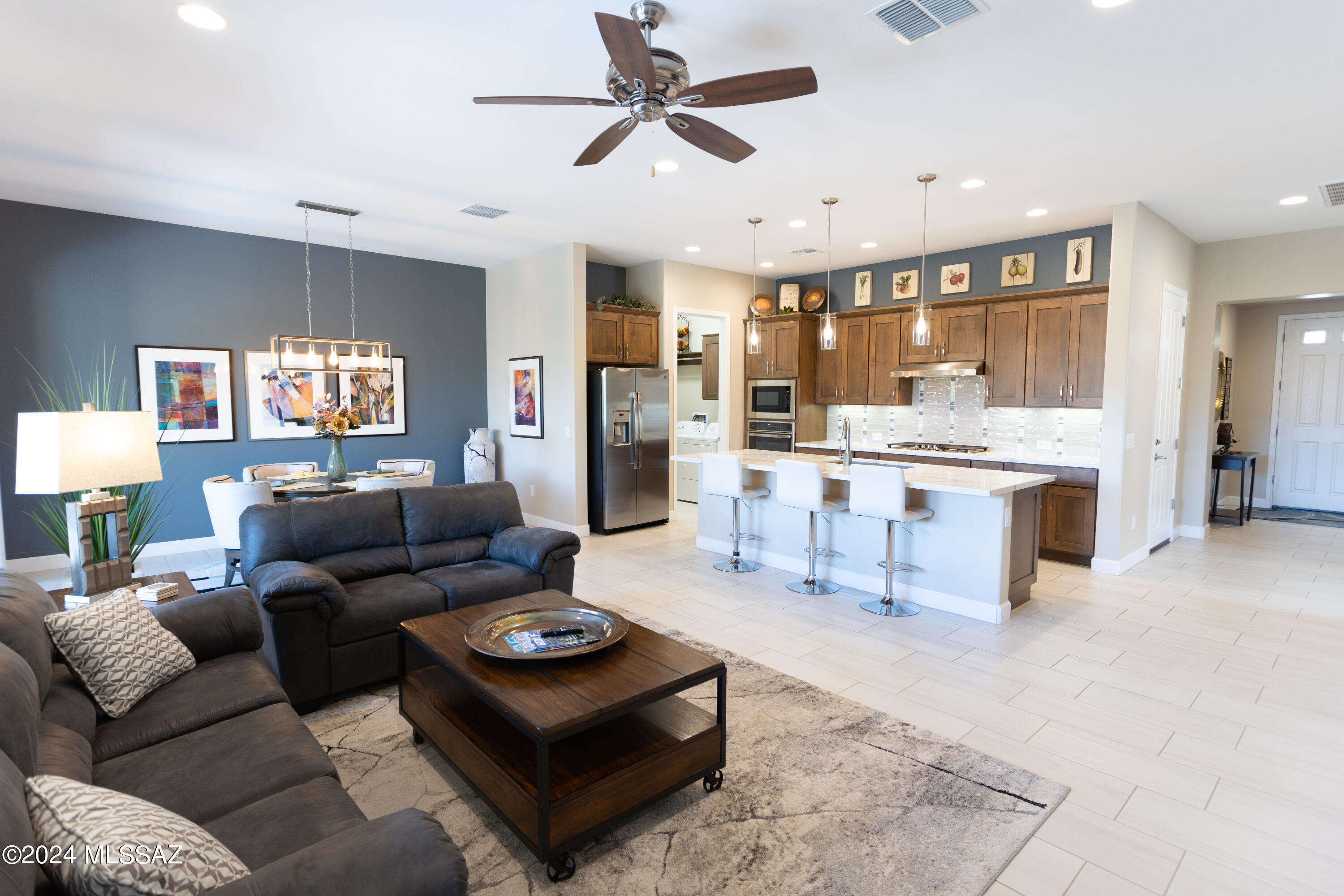 Unique custom features you won't find in others!  Start with the kitchen of this beautiful Viva Villa that has a gas cooktop, upgraded range hood, an electric/convention wall oven & microwave, pendant lights, quartz countertops, full tile backsplash, Blanco sink, trash & base cabinet drawer pull outs, walk-in pantry w/five tier shelving on two walls.  Walk into the primary bedroom w/custom space saving barn door closure to bathroom.  Bath has linen closet & full tile curbless shower w/end door.  Fully pavered patio backed by trees in the common area for privacy, spacious side yard.  Garage includes utility sink & overhead storage racks.  High end Aquasana water purification system!!  Home has a den/office.  Refrigerator, washer, and dryer are all included!  This one won't last!