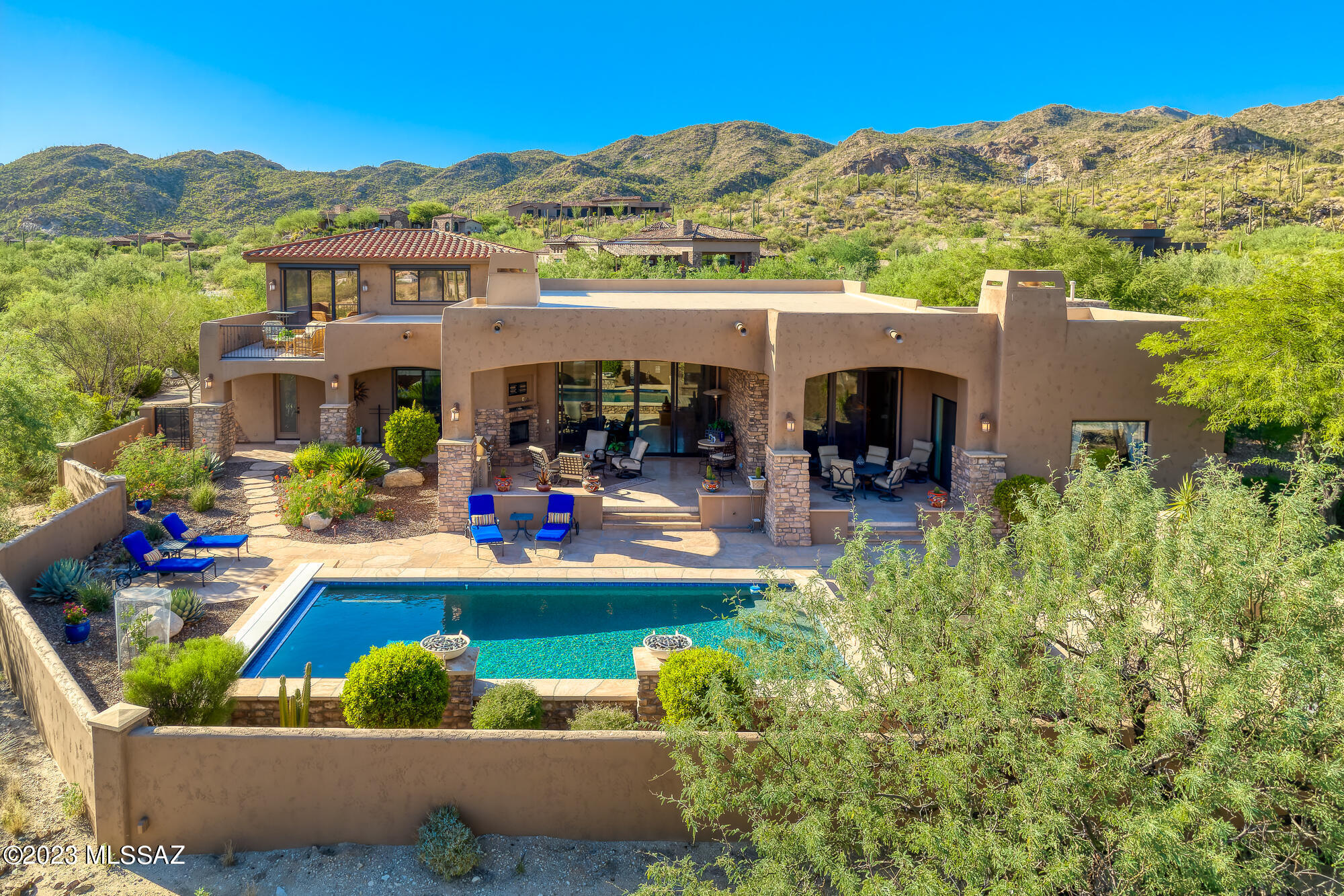 Serene views of Catalina Mtns and saguaro! Great room design with high ceilings & walls of windows. 2024 updated Chef's kitchen with new SS Sub-Zero & Wolf appls, custom soft-close cabs, under cab lighting, 2 ovens, M/W Dwr, gas cooktop, prep sink, large pantry, wine ref & sep wetbar. Travertine floors thru-out flow seamlessly onto deep cov'd patio w/Fpl, TV area, BBQ kitchen, multiple seating areas & misters. Large enclosed yard w/self-cleaning pool & 2 fire bowl water features, new automated cover, portable spa. Split 4,349 SF layout includes generous primary (updated bath), 2 guest suites, sep formal dining rm, den/office plus huge loft level BR#4/rec rm w/bath, kitchenette & observation deck. New water heaters, 3 HVACs & mini-split in oversized 3-car garage. Wonderful privacy & views!