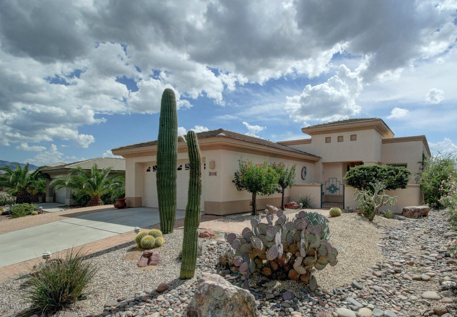 Flowing river rock and cactus gardens against a backdrop of sleek roof lines and Mediterranean Spanish Architecture will have you anxious to see the inside of this beautifully designed home. A wide foyer transports you into a sunny great room designed for fun with each wall providing light and nature through numerous picture windows. A perfectly placed dining area for easy serving and large terra cotta colored tile flooring combine to give you the warm feeling of home. A contemporary kitchen features gleaming stainless steel appliances for quick cleanup and a walk up counter bar so you can chat with friends while whipping up a delightful meal. Bay windows adorn your master bedroom while the bath with double vanity, separate jetted tub and walk-in shower creates a peaceful sanctuary.  The functional den is a great place to catch up on some bookkeeping. There is also a built-in desk area with wonderful cabinetry for additional computer or craft work. Enjoy your time outdoors in the front courtyard or on the private covered patio to relax in the shade and enjoy the fresh air.