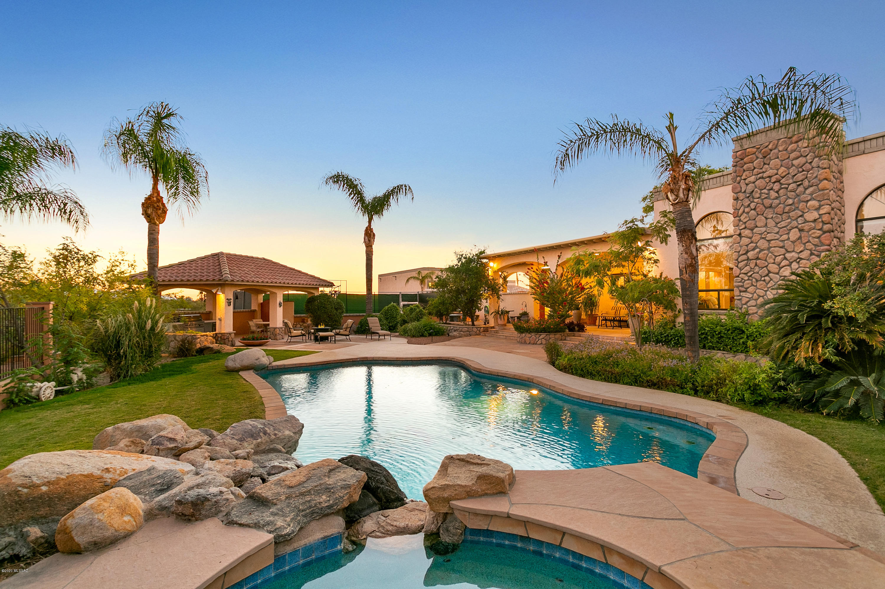 Nostro Mundo means 'Our World' in Italian...and that is just what this stunning 8.05 acre property with all things imaginable will be for your family! A Custom Masonry Home with Metal Interior Framing invites you through the front security gate, then along the aggregate driveway taking you past the oasis of vegetation, the lovely outdoor palapa sitting area, rock fountain and around to the 3 car garage attached to the main house AND a 4 car/RV garage and entire workshop with car lift and air compressor! The main house features 5073 square feet of greatness! 5 bdrms, which includes a gym an office & 5 bathrooms, plus an additional full pool bathroom outside. The updated open kitchen features granite counter tops, a huge island with wine fridge, top of the line Viking appliances, 36'' gas range & oven plus 30" wall oven and microwave. Built-in Sub-Zero refrigerator and separate Sub-Zero freezer, walk-in panty, enormous windows with gorgeus mountain views. Formal dining room sits next to the grand foyer and large open great room with 12' soaring ceilings. Don't forget about the huge game/rec room with built in glass/display cabinets and wet bar sink and undercabinet refrigerator. The backyard is another giant playground with a huge extended covered patio, pebble tec salt pool, hot tub, lush grass areas, covered gazebo, brand new BBQ kitchen area and half court basketball court! The side yard has a fully enclosed dog (pet) safe potty area with doggie door leading out of the master bathroom. Walk across the driveway to the guesthouse and fall in love all over again in this beautiful Italian Villa. The lush court yard has a gas fire pit under the covered palapa, built in BBQ and high top bar area, covered patio and separate laundry room with stack washer & dryer, built-in vacuum and alarm systems. Venture up the spiral staircase to the roof top deck to enjoy sunsets, city/mountain views, while enjoying your morning coffee or evening cocktail. The 1 bedroom 1 bath Villa has a complete kitchen, well apointed appliances, granite countertops, sound surround, plantation shutters, travertine tile and access to the 4 car/RV garage with workshop area, that includes a car lift and and air compressor. An abundance of delicious fruit trees are amongst the lush vegetation of over 50 palm trees, mature trees, bushes, and desert plantings!! The current dirt road to property is scheduled to be paved.