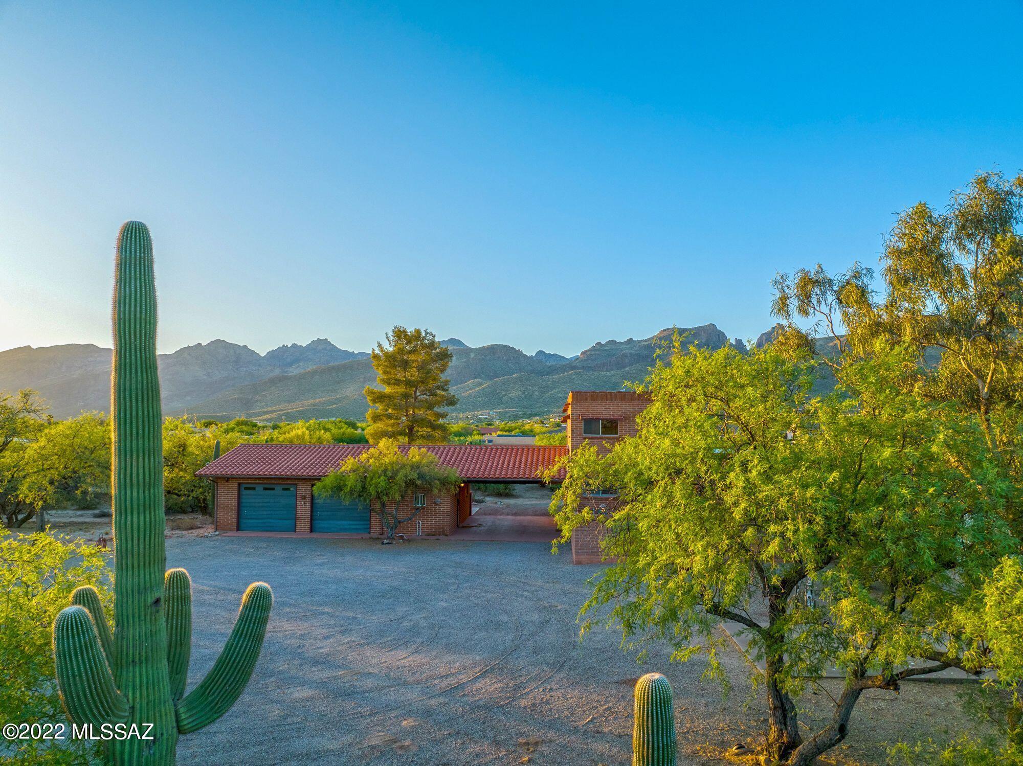 Beautiful property zoned for horses, with room for corral, stables, barn, pool plus guest houses! No HOA. This is a gorgeous SIX ACRE parcel! Prime NE location-amazing panoramic Catalina Mountain views! Custom burnt adobe home, big shop/garage across drive-through carport. Garage has kitchenette area, laundry room + bathroom & storage. Home has gorgeous hand laid wood chevron design on ceilings, a passenger elevator w/ solid, quiet, custom-built spiral stairwell. Two bedrooms down, one upstairs w/bonus rm & roof deck. Recent improvements: new leaching field & septic tank 2022, Additional workshop/sheds plus RV pad & hook ups + basketball court. This saguaro and mesquite studded land has so much potential!!!