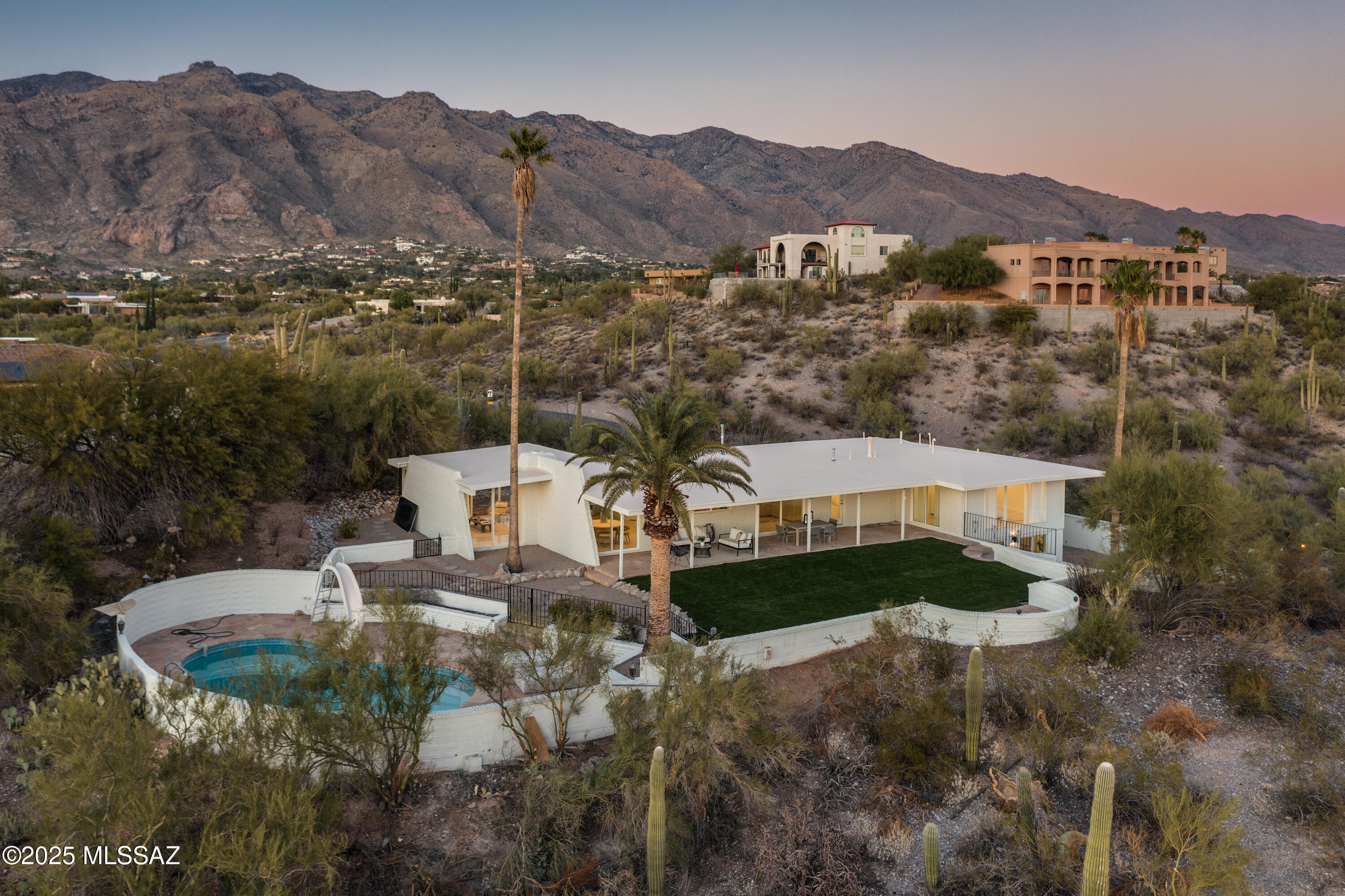 If you're looking for a home that stands out—this is it! Perched on a prime high lot in Bel Air Estates, this architectural beauty was the second home ever built in the neighborhood and has only had one previous owner before its stunning Mid Century Modern full remodel. Located within the highly sought-after Catalina Foothills School District. With floor-to-ceiling windows, panoramic views of Finger Rock and the Tucson skyline, and an abundance of natural light, this home is designed to impress.
Inside, the open-concept living area offers breathtaking views from every angle, complemented by a custom plastered wood-burning fireplace that seamlessly flows into the dining and kitchen space. The chef's kitchen is a dream, featuring custom cabinetry, two pantry cabinets, marble countertops, a 6-burner gas range, pot filler, built-in dishwasher, and a Café refrigerator.
Upstairs, you'll find four spacious bedrooms, including a luxurious primary suite with expansive city-light views. The primary bathroom is a spa-like retreat with a soaking tub, separate shower, double marble vanity, and designer finishes. The bonus downstairs room makes for a perfect fifth bedroom, guest suite, or flex space with its own bathroom.
Step outside to enjoy the newly replastered pool and pump, artificial turf, and a lower-level yardperfect for a fire pit or garden. Additional upgrades include: New dual-pane windows & doors, Custom aluminum garage door, Freshly recoated roof, New electrical meter, Chip-seal driveway, and 1-year termite warranty.
Plus, enjoy community amenities like a pool and tennis courts. This is more than a homeit's a mid-century modern oasis. You won't beat these views at this price! Owner/Agent