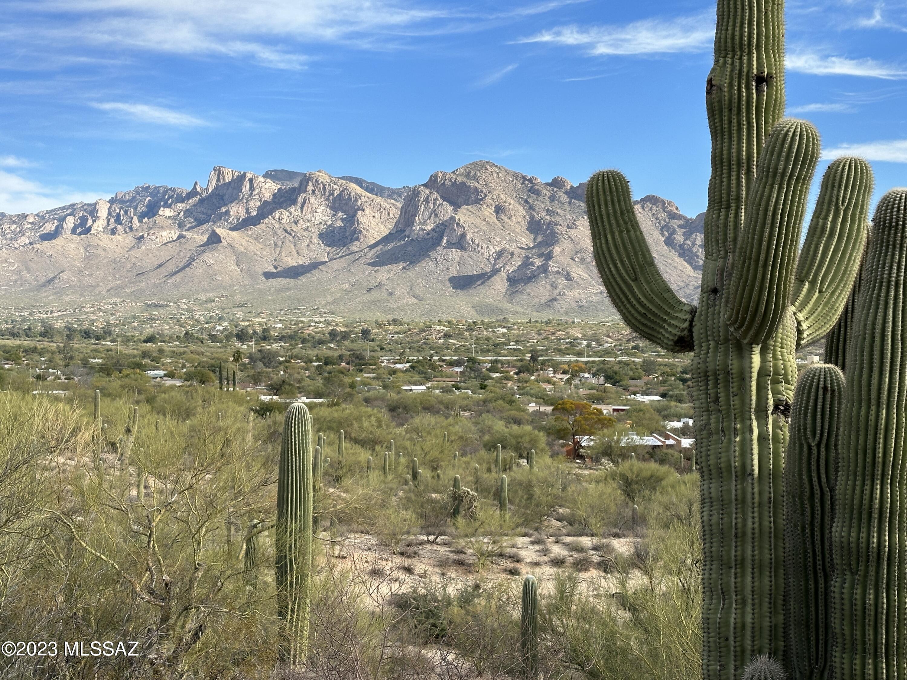 Rare opportunity!! Perched atop a hill in Oro Valley, this one-of-a-kind, four bedroom, three bath, 2722 square foot adobe brick home has simply one of the most jaw-dropping and expansive views in town! The 4.81 property is stunning—rolling hills studded with dozens of towering Saguaros, unobstructed Catalina Mountain views and twinkling city lights at night.  One of the owners is a fine art photographer who has captured hundreds of truly outstanding images from various locations around the property. 
Large, covered patios at the front and rear of the home offer respite any time of day from the sun or other elements. The semi-enclosed front patio with a latilla ceiling could be fully enclosed if desired for even more living space. A large living space at the front of the home has windows overlooking the front patio and a beautiful floor to ceiling fieldstone fireplace. Adjacent and open to both the front living space and the kitchen, the dining area has a sky-lit ceiling inset with picture frame molding. 
The remodeled kitchen boasts cherry cabinetry with decorative molding, granite counters and deep granite slab sink, wood-clad range hood and all appliances. A thoughtfully designed dining bar is positioned to take advantage of the views and a built-in desk area allows for multi-tasking. All appliances are included. The adjoining laundry room features more cherry cabinetry and a utility sink. There is also a remodeled ¾ bath with fully tiled shower and pedestal sink in this area, with convenient access to the garage and the rear yard.The family room amps up the cozy factor with its kiva fireplace, wood-beamed ceiling and vintage built-ins (with wet bar!). French doors offer access to the covered rear patio which runs the length of the home, perfect for entertaining. 
Wake up to gorgeous mountain views in the primary suite and step through another set of French doors onto the patio. Complete with its own ensuite bath featuring a walk-in shower and dual vanities with granite counters and vessel sinks, this bedroom also has a walk-in closet with built-ins. 
Three additional guest bedrooms are serviced by a full hall bath with wall length dual vanity and a vintage tile tub surround. One of the bedrooms has a wall of built-insuseful for a bedroom, office or craft space. Vertical glass block windows allow for light in the large three car garage and there is also an additional storage/workshop room. Excellent locationin addition to all the extensive amenities that Oro Valley offers, your new home is also near the world-famous Tucson Omni National Golf Club & Resort, the Northwest YMCA and the soon to be reimagined Foothills Mall.   Make this extraordinary property yours today!