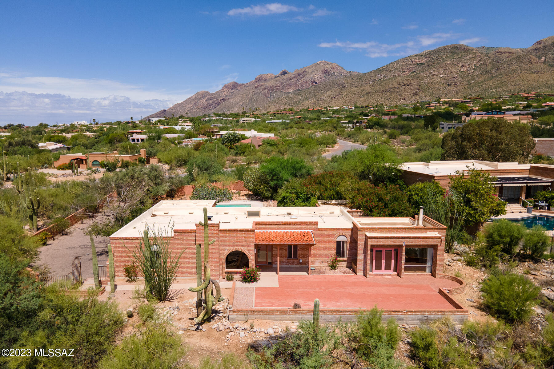 Nestled in the Catalina Foothills, this home enjoys unparalleled mountain and city views! Location is ideal - walking distance to La Encantada and Manzanita Elementary, minutes from multiple hiking trails and only 7 miles to UA campus.  Spacious primary bedroom has its own sitting room/office. Living room and large family room each have their own fireplace. Saltillo Tile and Mortar Washed Adobe. Brick patio and lush fenced pool area boast spectacular mountain views. Property is fenced and walled for privacy and to keep out desert critters, with mature trees and desert landscaping.
