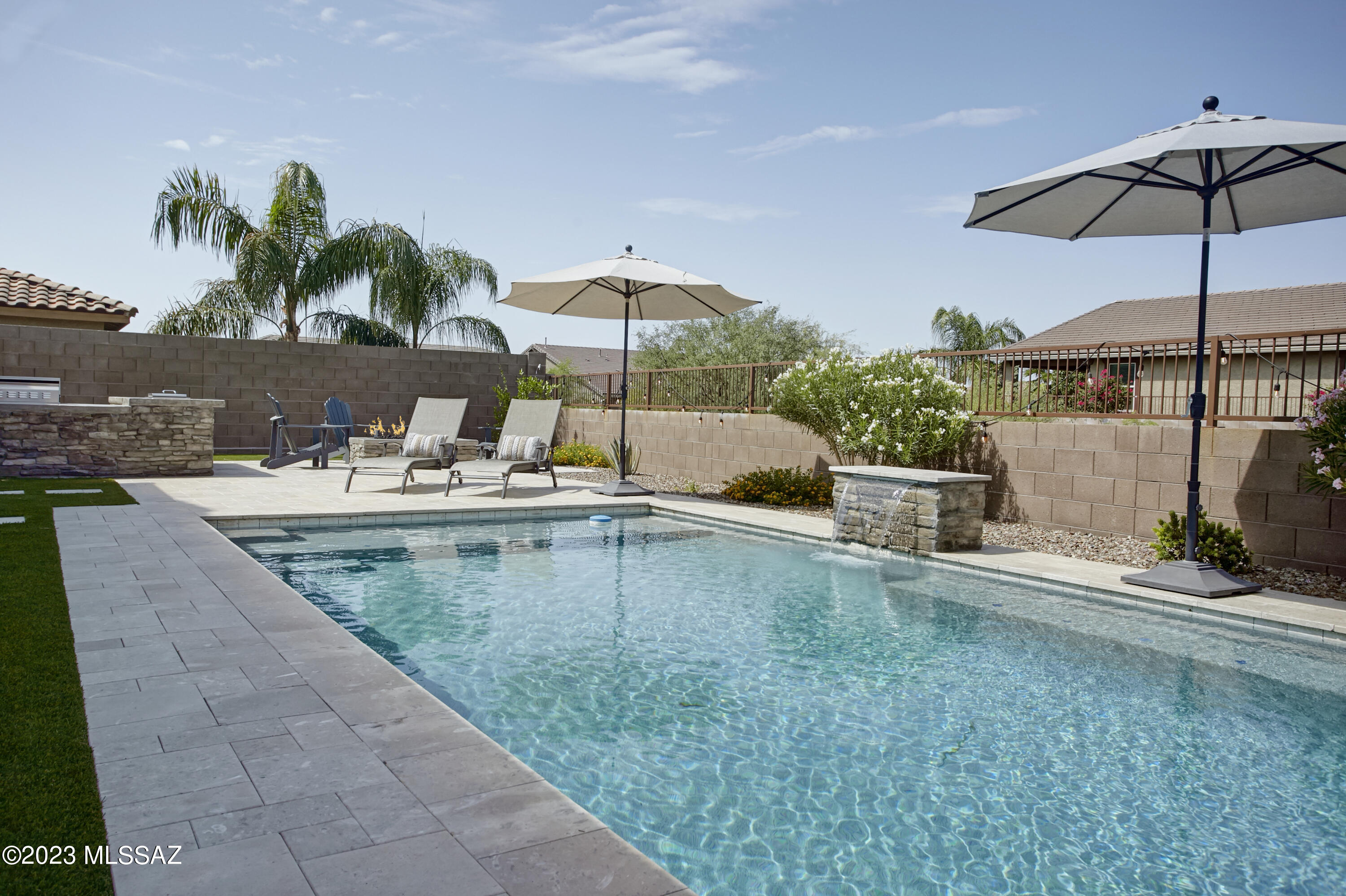 Inside the gated community, ''The Estates at Capella'' a unique opportunity awaits at 11011 N Gemma Avenue. Spacious properties such as this home seldom come to the market. Built in 2016, this two-story, 4,125 square foot, 5 bedroom, 3 ½ bath home provides various layout possibilities for modern living. The lower level includes 3 distinct & separate spaces with plank tile flooring that could be used for living, dining, play, or work. Lovely, upgraded granite countertops are found in the chef's kitchen, along with a butler's pantry and an enormous walk-in pantry. A downstairs primary suite includes dual vanities, a separate tub & shower, and a generous walk-in closet. The 2nd level provides 4 additional bedrooms and 2 full baths, as well as an airy loft and pocket office. Access from the interior to both the 2-car and separate 1-car garages create flexible use options, such as a home gym, workshop, art studio, or storage.

The backyard has been completed to perfection. Added in 2020, the custom designed pool surrounded with limestone decking features pebble-tec enhanced with abalone shells creating a subtle shimmer, two water features, and Leviton app-controlled lighting.  An outdoor kitchen with a built-in grill & beverage cooler is well situated next to a seating area with a gas fireplace - an ideal entertainment area. Greenspace behind the home provides a buffer and open feeling.

Sitting immediately west of the neighborhood is Ironwood Ridge High School (thus it is walkable), and immediately to the east is access to a paved multi-use path that connects to "The Loop." Within 2 miles, you will find the Oro Valley library, Naranja Park, and plazas with grocery, dining, pharmacies, and other services. This location boasts all the benefits of living in Oro Valley, while sitting a bit further south with immediate access to La Cholla Blvd, making commuting or traveling Downtown quicker.
