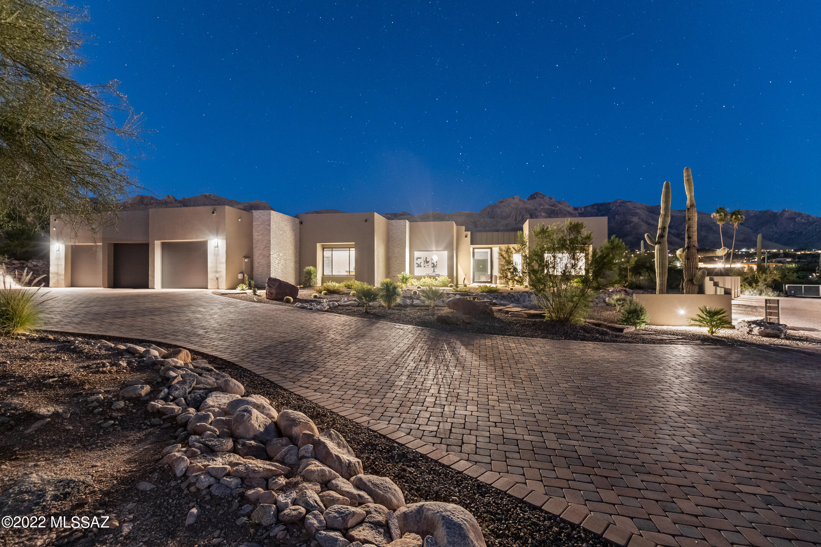 Step into the spring season with a gorgeous new Catalina Foothills home. Almost floor-to-ceiling windows capture the dramatic mountain backdrops while cozying up to the color-changing remote-operated fireplace indoors. Mood lighting can be set with ambient crackling sounds to mimic a roaring fire without the heat or fuss of a wood-burning fireplace. Entertaining abounds with the open floor plan and seamless indoor-to-outdoor transition space with top-of-the-line surround sound system. Heated saltwater PebbleTec pool and spa are equipped with custom lighting features to set whatever mood delights the moment. Control everything from a simple app on your phone while home or away. Buyer to verify all facts+figures, incl those in MLS. Custom designed outdoor Coyote grill and barbecue station with marble surround specifically designed for direct sun, including bar seating to house your guests while you prepare your main course. Adjacent gas firepit with coordinating marble finish casts flames from a bronze crystal base.

Beautifully epoxy-sealed garage floors with lifetime upgraded sealer coating match the neutral tones of the landscape. Enter through your exquisite over-sized 10' premium pivot glass front door, an entry that stuns every time. Thrill with the soaring marble tiled columns that transition the look from outdoor to indoor, and seamlessly tie into the front-facing facade for a jaw-dropping cohesiveness in thoughtful and creative desert contemporary design.

Chef's kitchen boasts a professional 48" 8-burner Capital range with gas cooktop and two electric ovens, a most desirable combination for preparing meals. Blanco undermount SILGRANIT in Anthracite main and prep sinks with Hygienic+Plus surface protection. Whole-house water filtration system. Both sinks are appointed with matte black Brizo faucets with knurled pull-out spray nozzles in the Brilliance Luxe Gold finish, complementing the Franke pot-filler over the Capital range. Two-toned Cleaf kitchen cabinetry, including a generous buffet design with added storage to fit the most extensive collection of dinnerware and entertaining accoutrements. Truly an entertainer's dream. 

Formal dining room astounds your guests, as you graciously seat large parties to the backdrop of sunset skies and peek views of the Tucson Mountains to the west. Eurofase TRENTO 15-light chandelier in Champagne Silver is an artistic focal point of its own. Generous closet is ready to be transformed into a wine room with temperature control, or used as even more storage for your dinnerware and decor. Gallery walls with lighting and buffet nook offer creative options to bring the space to life in just the way you imagine.

Each bedroom is en-suite with over-sized full-entry closet space and views from each window. Zero-entry showers, each with its own unique tile design and matte black Delta fixtures. Floating vanity and quartz counters are softly illuminated by hand-chosen Orren Ellis Pernini seeded glass lighting. Fourth bedroom is currently used as an art studio, with french doors and views to the sunset mountains to the west, but is wired and prepared to be an impressive media or game room with audio/video/electrical supply and a shelved closet for the equipment necessary. Sliding barn door tastefully conceals the utility and laundry room with sink and built-in cabinetry, gently lit by a recessed skylight.

Enjoy privacy on the eastern wing of the house in the generously-sized primary bedroom with color-changing fireplace crystals, motorized custom blinds and 5th bedroom adjacent perfect for a home office, nursery or study. Pendant Euroface HANSON bedside lighting with clear-seeded glass adds an element of delicate elegance. Primary closet has floor to ceiling CLEAF cabinetry in rare-to-find Italian Linnette finish. Center island with Linnette top finish is illuminated by the Eglo CARDITO 39" LED Crystal Linear Chandelier that is truly a gem of a piece. The primary bathroom is a luxurious retreat after a long day. Oversized floating vanity provides drawers of storage, uniquely designed to utilize every possible square inch of space for your amenities.
Zero-entry shower with matte black rain feature, handheld showerhead with slide bar and separate soaking tub, both framed with picturesque mountain views. 

A truly remarkable design by Greg Simmons, this home is a sacred refuge off the beaten path. For those desiring Pima Canyon views without the exposure or any restrictions from a homeowner association (HOA), this gated and private journey will be yours to envelope yourself in for decades to come. Minutes from high-end dining and upscale shopping at La Encantada, you are right in the heart of the Foothills corridor. You are among the elite financial advisors, the fine art galleries, the world-renowned resorts and spas and Tucson's infamous expansion of hiking trails and climbing spots. Catalina Foothills School District 16 is one of the most sought-after in the area for those with school-aged children. Do not miss this opportunity to pour into the coveted desert lifestyle.
Buyer to verify all facts and figures, including those in MLS.