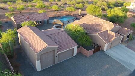 This one-of-a-kind home includes an updated 3-bedroom 2-bathroom main house, RV garage that spans 36ft wide by 40ft deep, heated in-ground pool, and a 2-bedroom, 1-bath guest house with full kitchen and laundry, nestled on a 1.5-acre lot with panoramic mountain views.  Step inside the main home with soaring ceilings creating a grand entrance to an elegantly updated home. Luxury vinyl plank lines the main areas of the home. The kitchen has fresh quartz counters and beautifully professionally painted cabinetry, newer stainless-steel appliances and a kitchen island that opens to the great room. The main home also features an office or formal dining room, as well as a den. Make your way down the hall to the main suite with romantic vaulted ceilings, a marble tile shower and quartz counters. This split bedroom floor plan also offers two bedrooms down the hall, both with spacious walk-in closets. Step outside to your very own desert oasis and entertainer's dream. The sparkling pebble sheen pool will keep you cool during the warm summer days and the therapeutic hot tub will keep you warm throughout the winter evenings. Frolic down the expansive paver patio to the guest house, built in 2019. This home features vaulted ceilings giving an open feel to the 864 sqft with all tile flooring. Encompassing a full kitchen with soft close cabinetry and granite counters, 2 bedrooms, 1 full bathroom, and laundry closet, the perfect hideaway for you or your guests to enjoy. Venture to the 1,440 sqft detached garage, complete with 50-amp RV service, a 14ft tall RV door with 16ft ceilings and a 9ft tall door with 10ft ceilings on the adjacent side, perfect for all your favorite toys and hobbies. This remarkable home has panoramic mountain views of the Catalina's from your backyard as well as city lights at night, step out your front door to view the majestic Santa Rita mountains and stroll the paved streets of Sahuarita Highlands, a wonderful community just outside city limits of Sahuarita with miles of OHV trails at your fingertips. Owner/Agent