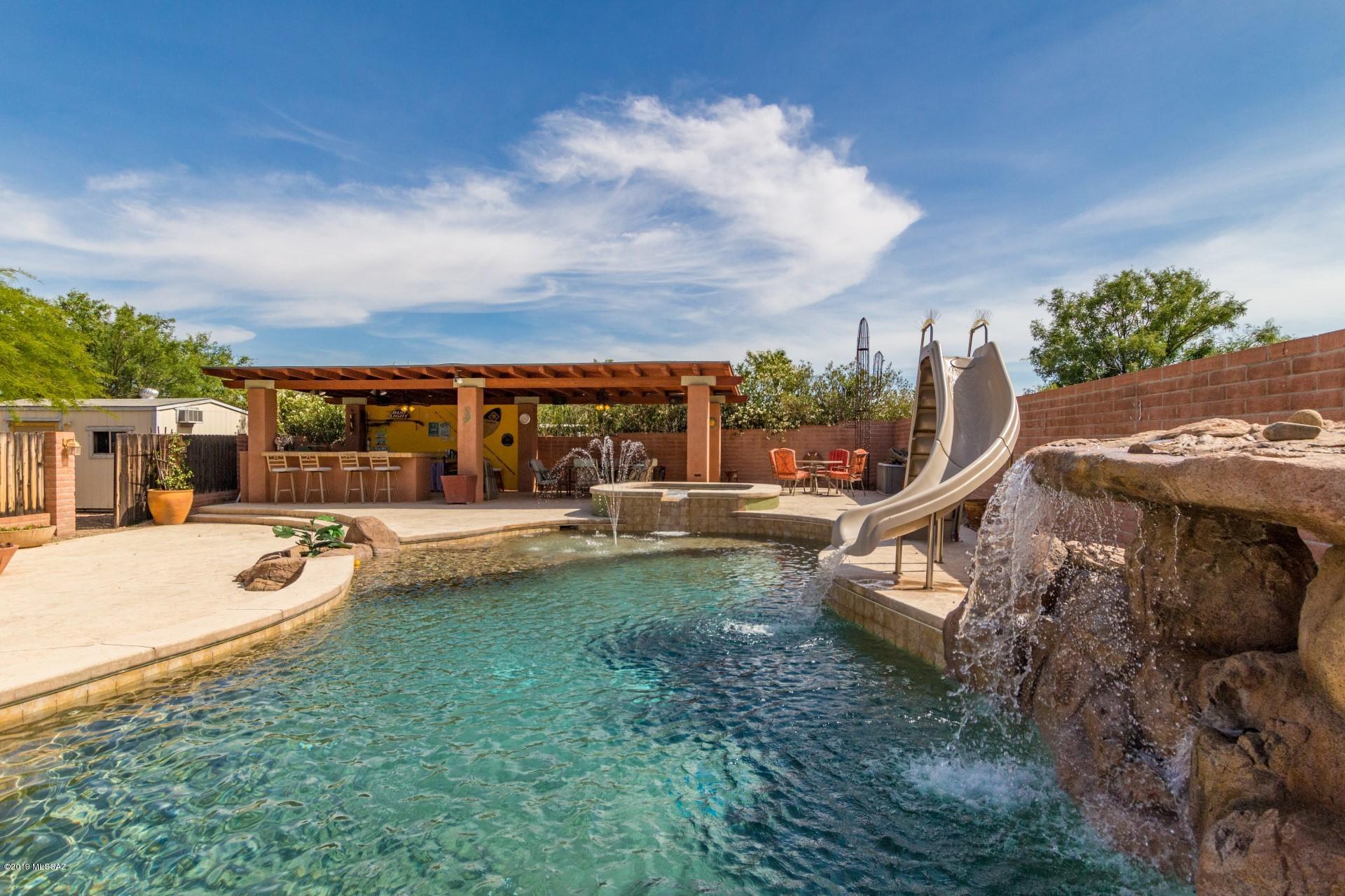 Great 5 bedroom home with resort like backyard featuring extra large pool, spa, pool slide, waterfall, covered bar/cabana, fire pit, plus deck. Enjoy spacious interior living: Living room, family room with fireplace, separate 2nd family room/game room, office, and large laundry with storage. Master bedroom & 2 bedrooms on the first floor, plus 2 spacious bedrooms and 3rd full bathroom on 2nd floor. RV parking, multiple parking areas, and workshop area. All this on a 3/4 acre lot in the peaceful Casas Adobes area, with easy access to shopping close by.