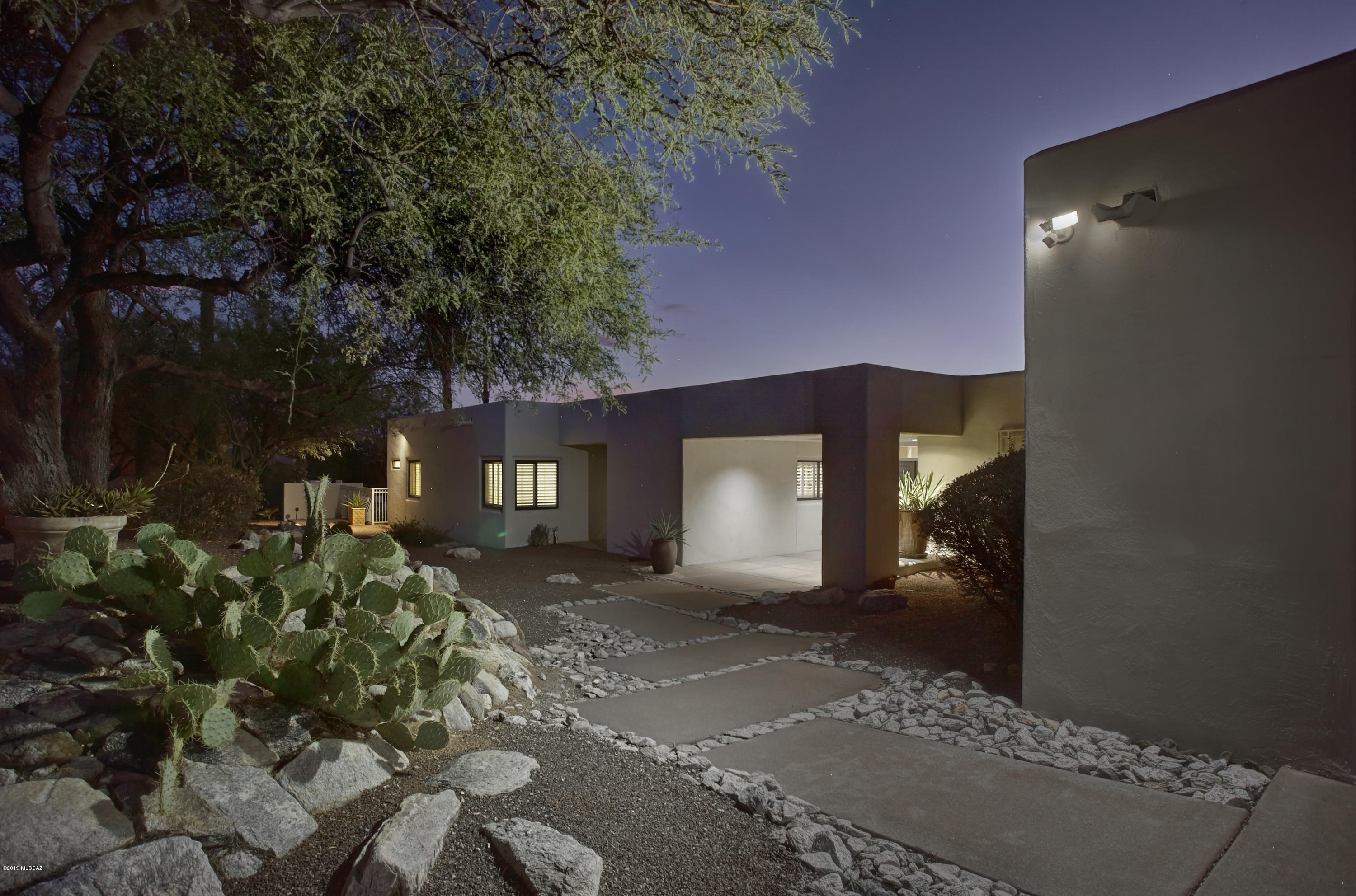 Nestled between million dollar homes, in one of Tucson's premier gated neighborhoods, is this stunning soft contemporary home built by Tom Doucette. Used as a winter retreat by the prior owners for 24yrs, this home has been lightly lived in, maintained to perfection & is immaculate! This casual, yet elegant home has magnificent mtn views & twinkling city lights from the master bdrm suite & rear patio. Light fills the rooms w/walls of windows, accentuating the beamed ceilings, fireplace, gourmet kitchen w/large island & wine bar. A library/media rm off the guest bdrm wing adds to its appeal. The luxurious master suite features an updated bathrm & large closet. Low maintenance landscaping & NO pool would also make this an idyllic winter residence just min from Ventana Canyon Country Club.