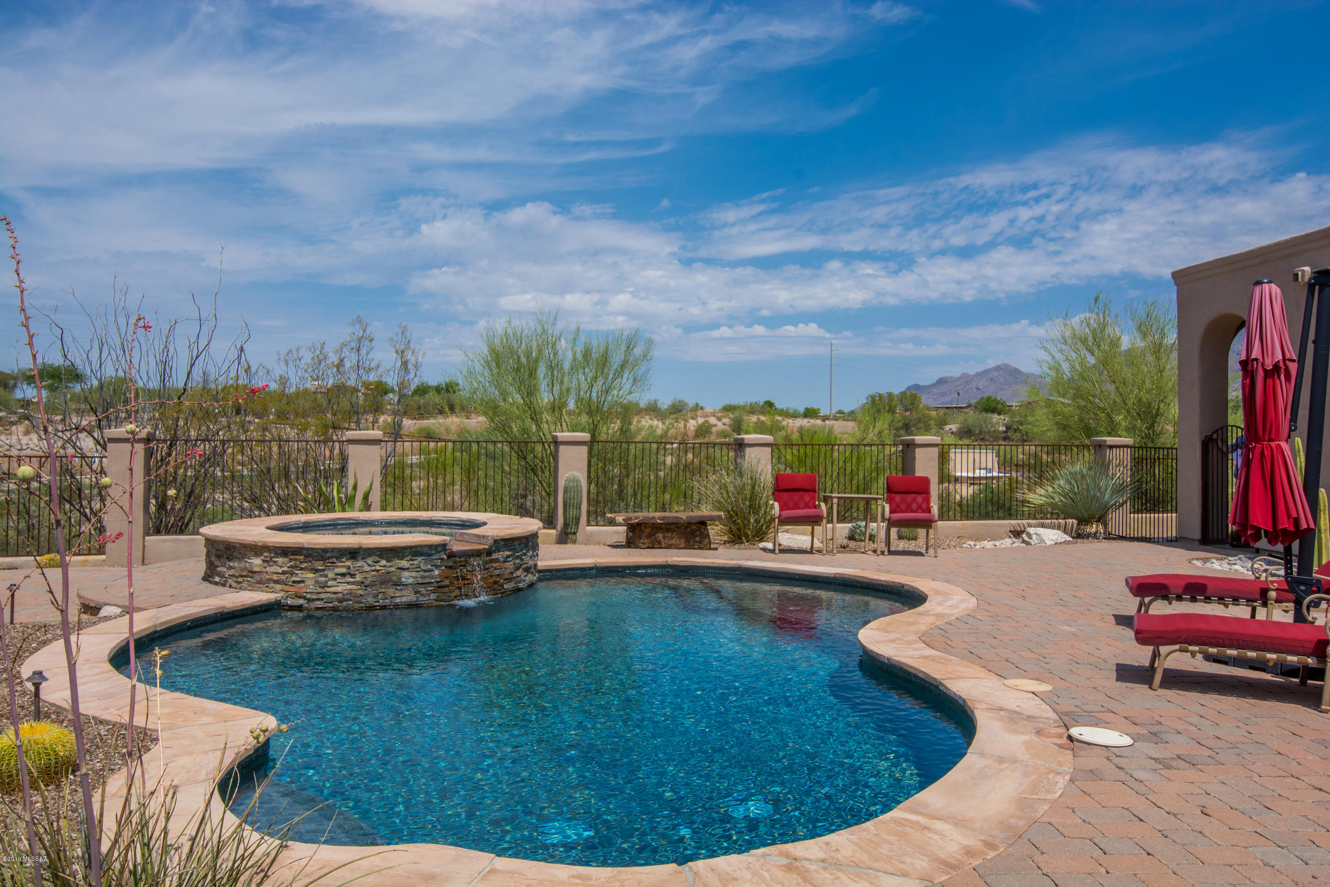 Take a 3D Virtual Tour of this magnificent custom hm w/private courtyard & fountain entry w/fabulous finishes thruout & great mountain & sunset views.  The rich wood beamed ceilings, travertine tile floors, gorgeous 8' alder doors, gourmet kitchen w/huge island, 5-burner gas cktop, chiseled granite counters, built-in wine rack, SS appl & designer pendant lighting are sure to impress. Luxurious Mstr Ste features stunning tile FP, Jacuzzi tub, dual sinks & limestone counters, lg walk-in shower & generous walk-in closet.  Don't miss the gorgeous stacked stone adorning the stately FP & signature ½ bath.  Enormous den/ofc has large picture windows.   Fabulous outdoor living w/massive covered patio, brick pavers, built-in BBQ, tasteful arches, great mountain views & wonderful pool/spa/waterfall