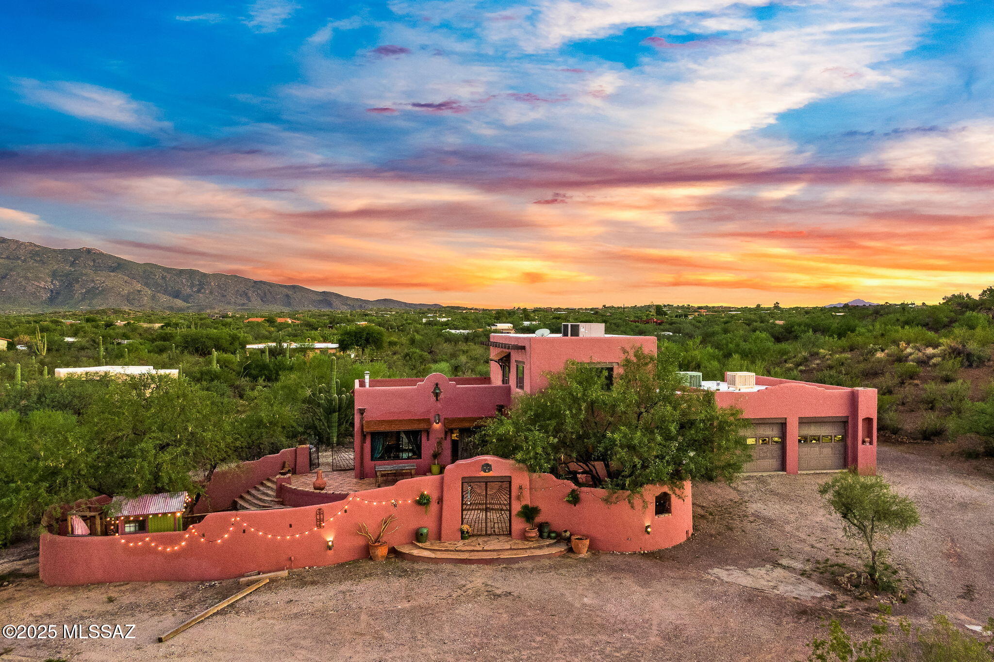 Experience the beauty and tranquility of this one-of-a-kind Southwest-style home on 5 lush acres surrounded by mountain scenery. Enjoy panoramic views of both the Rincon and Catalina Mountains, with sunsets that feel straight out of a painting. The main home features 3 bedrooms and 2 bathrooms, showcasing warm wood beam ceilings and timeless character. The primary suite spans the entire upper level, showcasing breathtaking views from it's own rooftop deck, while two bedrooms and a full bath are located downstairs. A large breezeway connects the main house to the guest studio and oversized garage/workshop. The guest house offers its own laundry, a large storage room below, and a private balcony perfect for sunrise and sunset viewing. Zoned for horses and free from HOA restrictions, this property offers endless possibilitiesadd a pool, expand the footprint, or simply enjoy the space as-is. The front courtyard is a serene retreat surrounded by mature vegetation and mountain viewsan ideal setting for peaceful mornings or entertaining under the stars. A true sanctuary; Perfect for cyclists, artists, or multi-generational living just five minutes from Saguaro National Monument East and less than ten minutes to Houghton Northwest Hospital, shopping, dining, and entertainment.