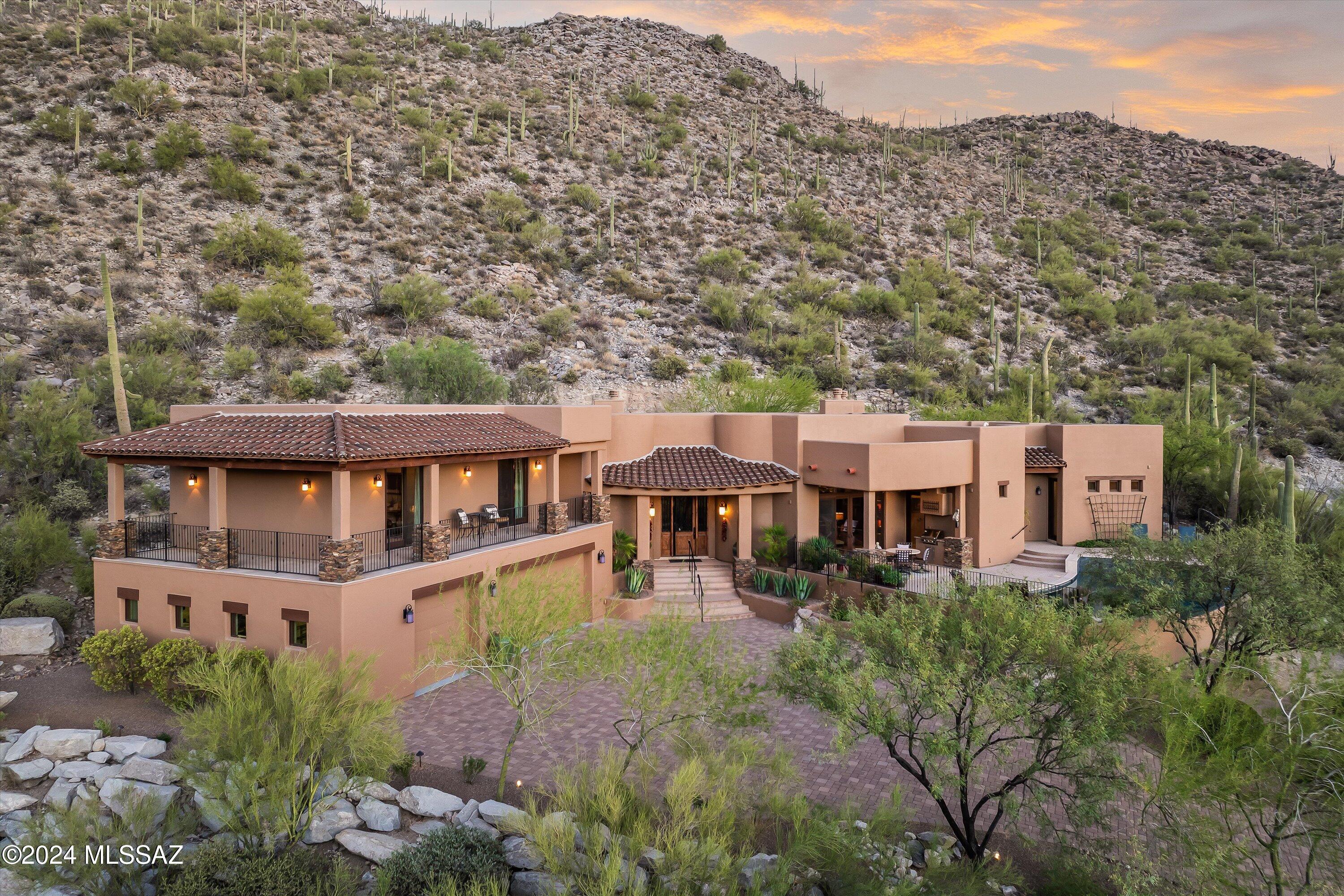 Experience luxury living in this stunning custom-built southwestern-style home, nestled in the hills of the Tortolita Mountains within the prestigious guard-gated community of Canyon Pass at Dove Mountain. Situated on a 1.89-acre lot, this home maximizes breathtaking views, offering an ideal oasis for those seeking a premium living experience.

This multi-level residence features four bedrooms and four and a half bathrooms, spanning 3,920 square feet. It showcases exquisite craftsmanship and custom finishes throughout, providing spectacular panoramic views of the Tortolita mountain ranges while overlooking the 5th fairway of the Gallery North Course. No expense has been spared in the construction of this home. It includes impressive finishes such as custom-made Knotty Alder cabinets and doors, custom ironwork, tumbled travertine tiles, and Hickory wood floors. Decorative wall finishes, hand-painted murals, and multiple window walls with sliding doors contribute to the beauty of the space, offering breathtaking views and ample natural light while facilitating seamless indoor-outdoor living.

The raised dining room is thoughtfully situated in the heart of the home to promote gatherings, offering a harmonious blend of comfort and elegance. It features beautiful hand-scraped hickory flooring, a stunning hand-painted tray ceiling, and custom-built display cabinets that enhance the space.

The dining room is open to the great room, which makes it perfect for entertaining. This inviting space features a stunning stacked-stone gas fireplace with a handcrafted mantle, a custom-built entertainment wall cabinet, a wine closet, and a sit-up wet bar. With expansive floor-to-ceiling windows and sliding doors that lead to both the front and rear patios, you can enjoy seamless indoor-outdoor living. The front patio includes a built-in BBQ, a vanishing edge pool, and a spa, offering stunning views of the Tortolita Mountains and unforgettable sunsets. Additionally, the private rear patio is a serene retreat, complete with an outdoor fireplace and a large fountain, all framed by stunning rock outcroppings and stately saguaros. This enchanting setting invites you to relax and enjoy the beauty of nature right at your doorstep.

The powder room is conveniently situated near the great room and pool area, designed to create a warm, earthy ambiance. This atmosphere is enhanced by the use of earthy tones, featuring a floating handcrafted wood vanity and a natural stone countertop with a chiseled edge. A handcrafted wood mirror adds to the aesthetic, while an engraved copper vessel sink and decorative wall tiles are complemented by iron sconces.

The open kitchen is truly impressive, showcasing custom Knotty Alder cabinetry, a stunning granite countertop with a decorative backsplash, and a hammered copper under-mount double-bowl sink with an apron front. It also features a breakfast bar, a six-burner gas cooktop topped with a copper range hood, a pot filler, and a spacious walk-in pantry. This kitchen seamlessly flows into the family room, which includes a stylish wood-burning fireplace, creating an ideal space for relaxation. A wall of floor-to-ceiling windows opens up to the covered rear patio, complete with a built-in BBQ, making it the perfect spot for outdoor dining. Adjacent to the kitchen and family room is an office nook that offers a dedicated workspace featuring custom-built Knotty Alder cabinets, shelves, and a desk with a granite top.

For added privacy, the primary suite is located on a separate floor in the south wing of the home, providing a true retreat. This suite features a double-door entry, hickory wood flooring, wood beam ceiling, and Venetian plaster walls. It also includes a gas log fireplace, a sitting area, and two custom walk-in closets. A laundry closet with a stacked washer and dryer is conveniently included, and a window wall provides access to an elevated rear patio area, which features garden beds. The ensuite bathroom is appointed with a double vanity featuring a granite countertop, a soaking tub, and a large walk-in shower that provides direct access to the spa and pool.

Two additional bedrooms are located on the upper level of the north wing. Both bedrooms feature walk-in closets and ensuite bathrooms with walk-in showers. They share a wrap-around balcony that offers sensational, unobstructed views. The fourth bedroom is tucked away on the ground floor in the north wing, off the hallway. It includes a ceiling fan, a double-door closet with built-in shelves, and travertine tile flooring. This bedroom has access to a hall bath with a floating vanity and mirror faced with natural stone tiles, a granite countertop with a stainless steel vessel sink, and a walk-in shower. Additionally, there is a laundry room with knotty alder cabinets, a hanging bar, and a soapstone countertop with a sink, along with a full-sized washer and dryer. The oversized three-car garage offers built-in storage cabinets, a workbench, a utility sink, a separate storage room, and an epoxy floor.

Discover unparalleled Arizona living in this exceptional property, where luxury meets comfort. With its exquisite custom details, serene privacy, breathtaking views, and timeless design, this home offers a lifestyle that is both elegant and inviting. 

Don't miss the chance to make this one-of-a-kind residence your own!