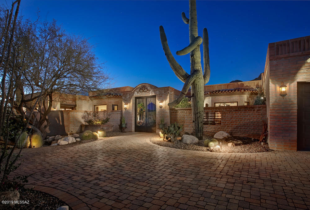 This delightful hacienda-style home in prestigious Pima Canyon melds casual lifestyle, quality of construction and attention to detail sought by the most discerning buyers.  The main house with 4BR/4BA features a great room with a Cantera FP, coffered ceilings a media room/den & stunning views.  A  separate 630 sq.ft. guest house boasts a living room, kitchen and a spacious 5th BR w/bath. Spacious master suite w/Cantera FP includes a spa-like bath, lovely outdoor shower and exercise room.  Gourmet kitchen with wine cellar, center island, custom cabinetry, Wolfe range, lovely tile, & 2 dishwashers is a chef's delight. The abundant outdoor space with outdoor kitchen, kiva fireplace, putting green, lush landscaping, a Zen garden, and solar heated salt water pool and patio are second to none.