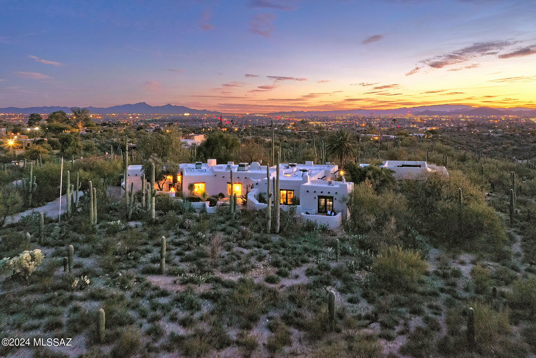 A stunning, classic 1936 adobe home in the old Catalina Foothills exudes the historic charm of Josiah Joesler's Santa Fe construction with modern enhancements.
The meticulous craftsmanship is exemplified by its adobe structure, 5 indoor fireplaces, rough-sawn wood beams and hand-forged metal fixtures.  Situated on a Saguaro studded 8 acre hilltop, this location is indeed rare and desirable. Enjoy breathtaking panoramic views of the Catalina, Tucson, Santa Rita and Rincon mountains, city scape and sunsets while embedded in a rich, diverse and private Sonoran Desert landscape.

This 5868 sq ft property offers a main house with 5 bedrooms/6 baths laid out with beautifully restored concrete floors. Each bathroom is accented with authentic Mexican tiles. A generous 10 ft ceiling and a large window frames the stunning view of Finger Rock from the spacious living room. A charming formal dining room brightened by handcrafted sconces opens to a large, open remodeled kitchen with a walnut butcher block center island, white shaker wood cabinetry, stainless steel appliances and soapstone counter tops. The south facing windows of the family room overlook dramatic cityscapes as well as the Tucson and Santa Rita mountains. Attached to the main house is a separate guest apartment with a private north facing entrance and patio. A separate 2 bedroom/2 bath guest house with full kitchen features an ample living space with Saltillo tile floors throughout and a large storage room. Outdoor amenities are showcased in multiple private courtyards, open and covered ramadas, outdoor fire places, a beautiful pebble tech swimming pool/spa, solar energy, and a horse stable now used as a workshop.
For those who appreciate Tucson's rich heritage, its remarkable architecture and the beauty of the Sonoran landscape, this desert gem situated on 8+ acres offers you a unique opportunity to experience a home with timeless elegance combined with modern comforts and luxury.