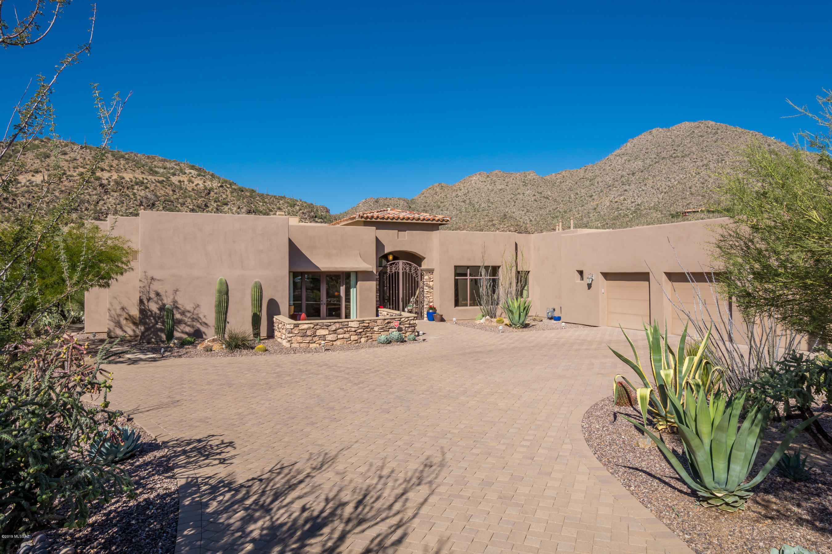 Impeccable custom home in gated Canyon Pass, 6th green of The Gallery North Course w/ amazing mountain views! Golf is ''essential'' in Dove Mountain. Iron gated entry leads to double glass entry.  All rooms have large windows for light & views! Great room w/Cantera accented FRPL.. Formal dining room. Kitchen features large island w/ micro, warming drawer, Wolf range, Sub Zero fridge, breakfast area, breakfast bar, wine bar w/ wine cooler. Mstr suite w/ FP, patio access, custom closet w/ drawers & cabs, separate vanities plus makeup vanity, jetted garden tub, dual shower heads. BRs 2 & 3 have en suite baths, walk in closets, Office w/ front patio access. Paver & travertine patio w/ close up mountain views, fire pit, BBQ. Garage w/ storage room plus heated & cooled STUDIO w/ sink.