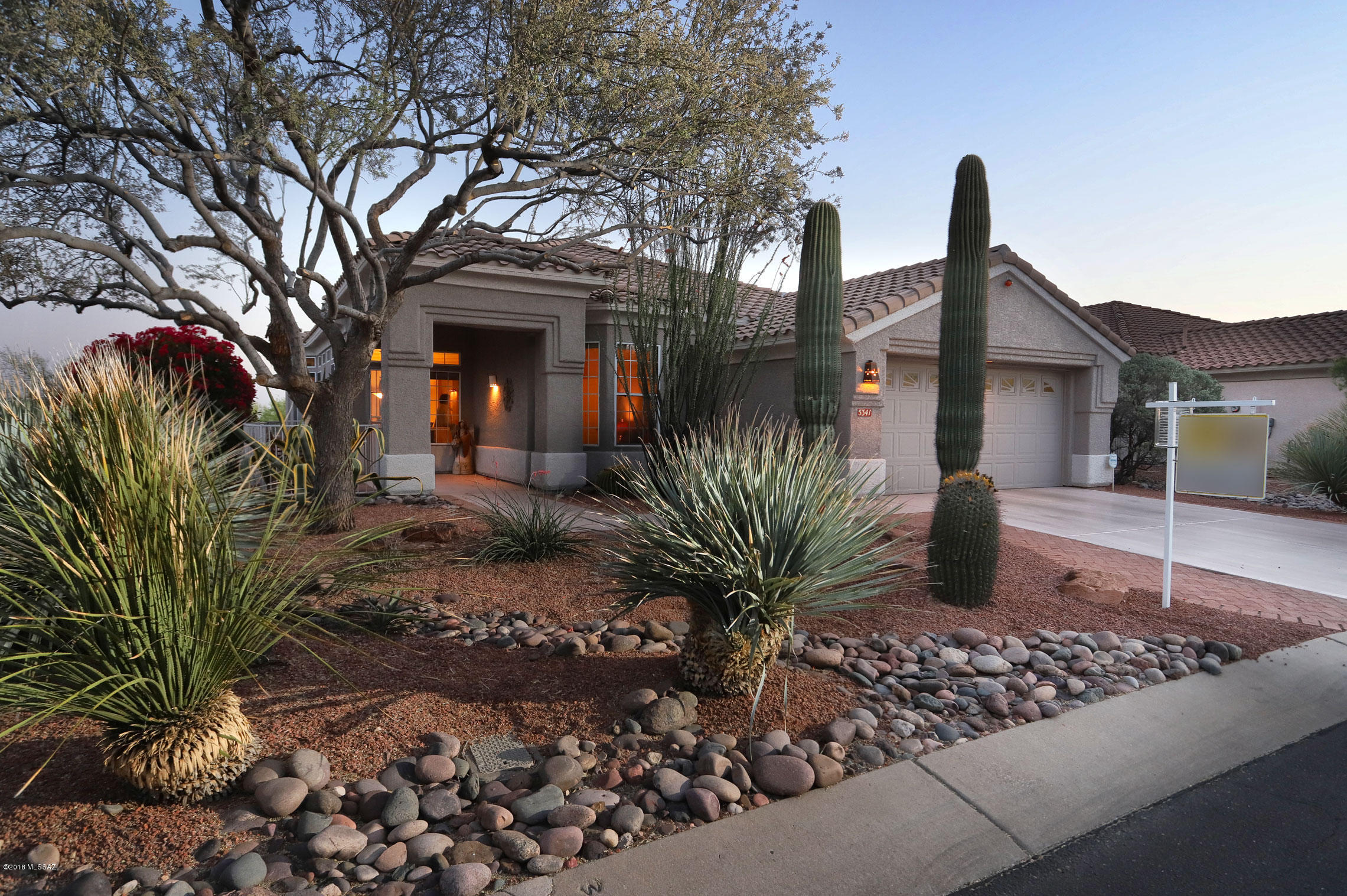 This sun filled and vibrant home in The Highlands of Dove Mountain offers a rare treat for the eye - both inside and out. Situated above the desert landscape, with views of the golf
course, Tortolita and Catalina Mountains, as well as the twinkling lights of the city in the far distance, there is a feeling
of privacy and serenity. The brick patio that extends the breadth
of the home is lushly landscaped with mature grapefruit and orange trees, a leafy olive tree and the various shrubs that attract hummingbirds and butterflies.Views of nature's bounty are in every window creating a bright, light and happy environment. Upgrades to the home over the past five years include stainless steel kitchen appliances, Maytag washer and dryer, HVAC, paint inside and out, a new drip irrigation system. and much more. The handsome, designer
furnishings and accessories are also available at a very
reasonable price. Just bring your toothbrush and start enjoying
the wonderful benefits of living in this very active over fifty five
community. The living and dining areas in this expanded Medford Model are
enriched by a triple coffered ceiling and accommodate a large
dining room table and comfortable seating. The spacious and
bright family room, separated from the living/dining areas by an
open wall design, has an attractive cozy fireplace that is perfect
for entertaining and family living. The adjacent breakfast area
opens to the "piece-de-la-resistance" of this delightful home, the expansive brick terrace with its multiple seating areas, charming
kiva fireplace and built in gas grill. The spacious master suite, complete with coffered ceiling and double walk in closets, enjoys a wall of windows with views of
the charming terrace. The large master bath offers both shower
and tub. The second bedroom has been expanded in this model to provide
virtually another master bedroom. That bedroom and adjacent
guest bathroom is well separated from the master suite.
The den easily accommodates a sleep sofa and a wall of double
desks. The laundry room, with newer Maytag washer and dryer,
has good storage and counter space. The two car garage has
wonderful built in cabinets and an epoxy floor for easy cleaning.The Highlands at Dove Mountain provides a coveted, active
lifestyle for adults age 55 and over. The attractive Clubhouse is
the center for outstanding evening entertainment: perhaps a big band
concert, country and western entertainers or a lecture. There are
hobby groups, book clubs, pickle ball, tennis, great fitness center, a fabulous pool area, a full service restaurant, meeting rooms, art studios, and of course a very popular golf course. A five minute drive will bring
you to the Ritz Carlton for a gourmet dinner or cocktails at
sunset. You are not far from the new Tucson Discount Mall for a
shopping expedition. Interstate #10 provides easy access to
airports, downtown Tucson or Phoenix/Scottsdale. Oro Valley is
close by offering more shopping, dining, movies and
outstanding medical facilities. You are invited to visit this very appealing and unusual home at your earliest convenience.
