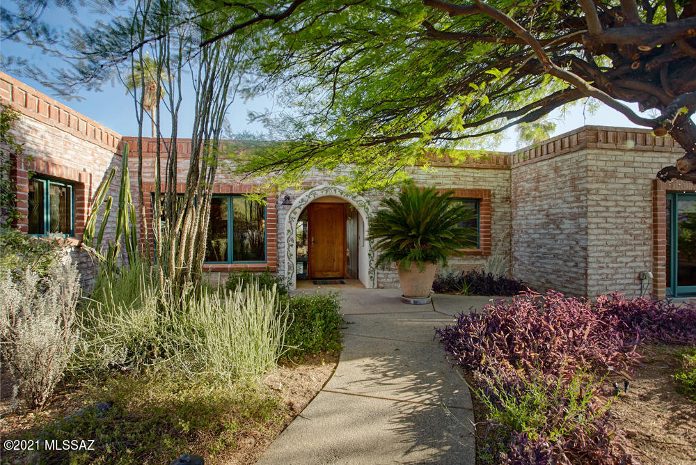 Classic foothills burnt adobe with a unique contemporary flavor.  Sited to capture city and mountain views, the property has a lushly landscaped front courtyard and is surrounded by lovely gardens.  The beautifully remodeled open concept kitchen w/custom cabinets, spacious center island, Thermador range, built in refrigerator and wine cooler is a chef's delight.  Two  master bedrooms with ensuite baths, walk-in closets are perfect for families or guests.  Enjoy Tucson's lifestyle at it's best in the backyard space featuring a  Pebble Tec pool, built-in BBQ, Ocotillo-ribbed covered patio, outdoor shower, and an cactus garden.    Brazilian rosewood floors and solid alder doors enhance the charm and warmth of this home.  Don't miss this great property!