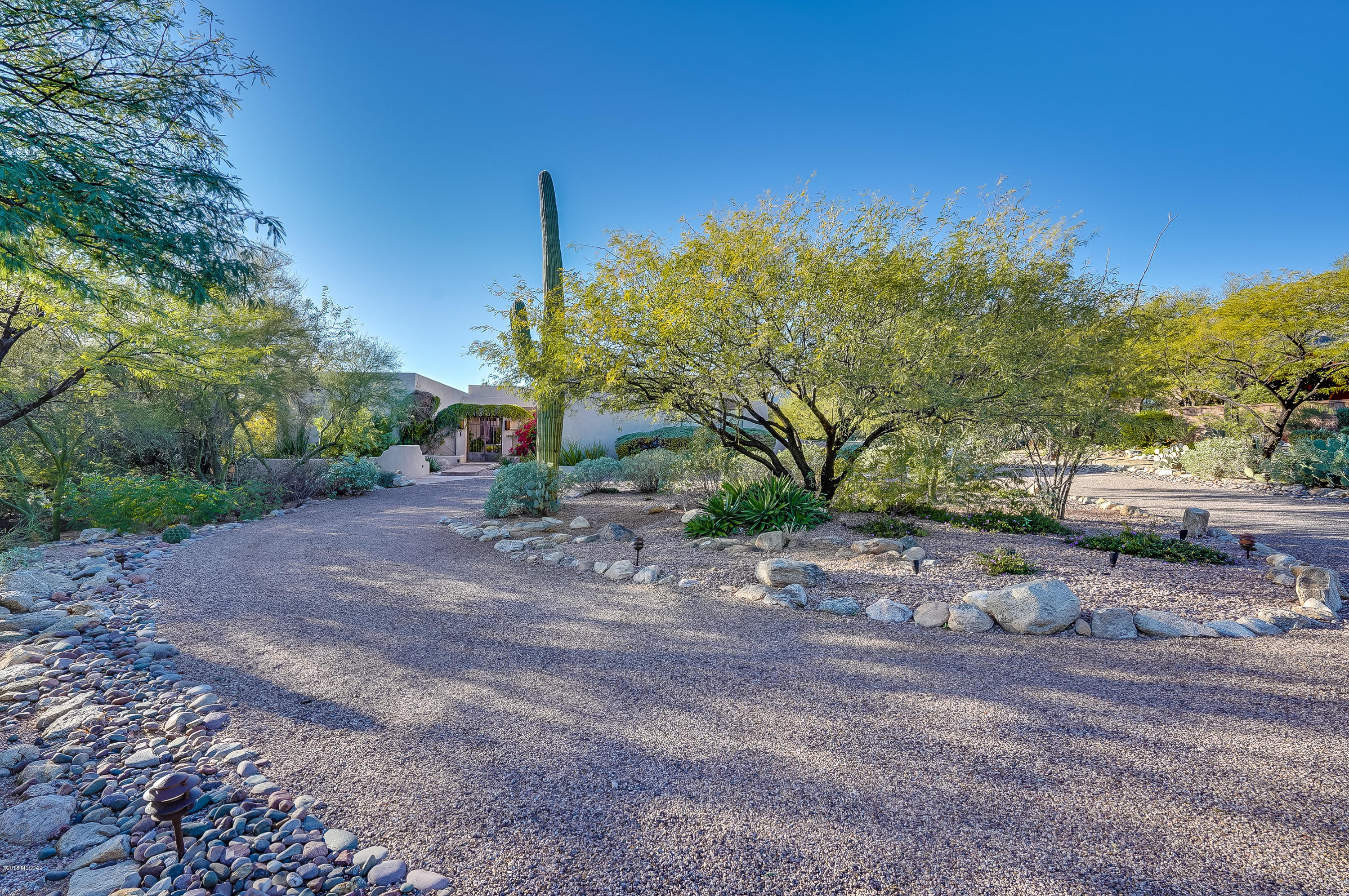 Updated, custom 4BR/3BA home, tucked away on over an acre of serene desert in  small, gated community at the base of Catalina Mtns.  Quality & craftsmanship throughout this thoughtfully designed split floor plan. Cook's kitchen has island w/ bar seating, stainless appliances, granite counters, wonderful breakfast nook, open to family room, pool & patio. Spacious master suite, w/ fireplace, private patio & luxurious bath. Good sized guest rooms w/ excellent closet space. Laundry room w/ pantry & wine fridge. Experience an Arizona Outdoor Living Room surrounded by lush, private resort-like backyard. Deep covered patios, multiple seating areas, fireplace, built-in BBQ, beautiful mtn views & endless hiking trails nearby. Very Private. Over-sized 3 car garage w/ huge storage room.