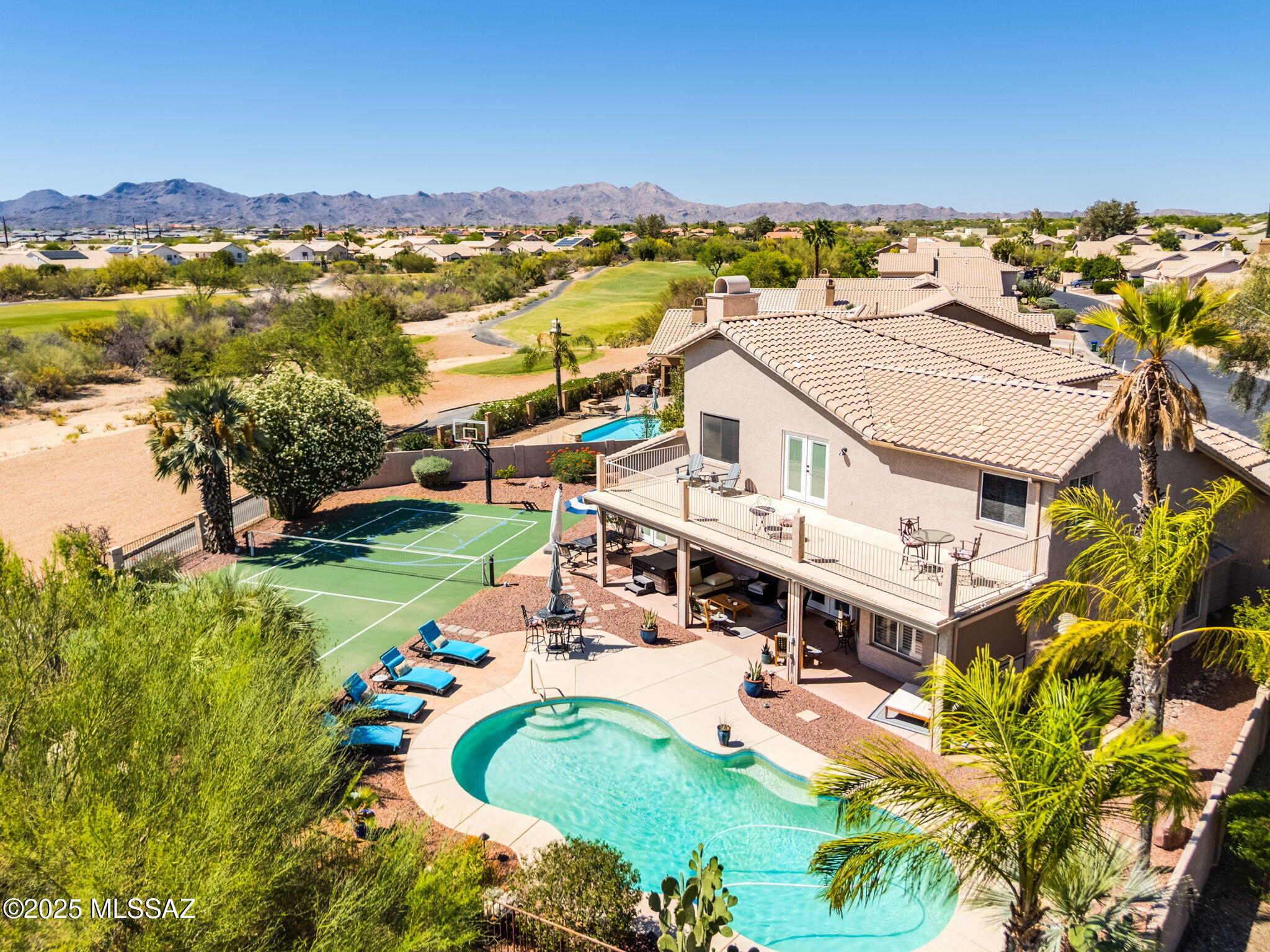 Luxurious 4BR/3BA+Den (3,811 sq ft) two-story home on golf course offers a new roof, no poly, resort-style yard with sparkling heated pool, hot tub & pickleball/basketball court plus panoramic mountain views! Soaring vaulted ceilings and spiral wood banister staircase greet you. Formal living & dining areas flow to an informal gathering room with media wall & wet bar plus gourmet kitchen hosting Breakfast Bar-Nook-Island, custom cabinetry and granite/stainless amenities. Upper level hosts private Owner's Suite with spa-like bath, fireplace & balcony with views plus 2 bedrooms, hall bath and Den. Large guest room on main level lies off a hall bath. Additional amenities include plantation shutters, bay windows, newer French doors, security features and 3-car garage with keyless entry. Relax on the covered rear patio with rolling sunshades overlooking lush landscaping plus golf course and mountain views. Close to Oro Valley Community Center, schools, dining & entertainment. A true desert retreat!