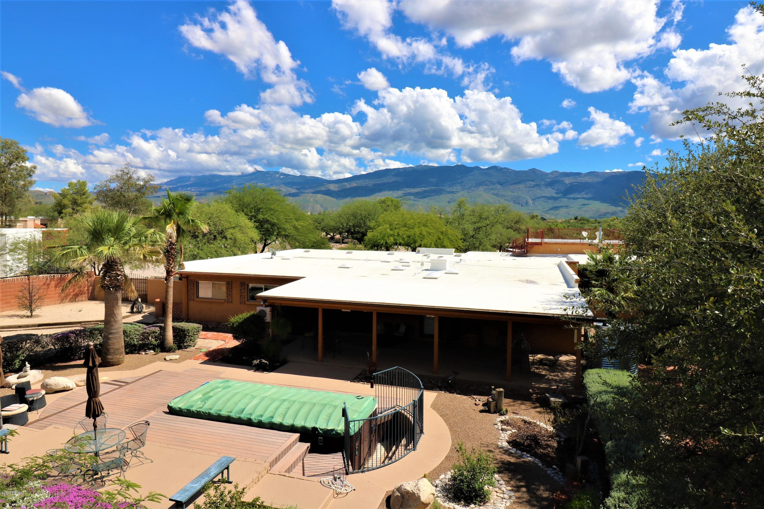 Charm and character runneth over in this lovely home situated on .85 acres with fantastic views of the Rincon and Catalina Mountains. This home's many features include beautiful archways,french doors, floor to ceiling brick fireplace, gleaming saltillo tile floors, warm paint & decor, split bedroom floor plan, master suite w/bonus room, large guest bedrooms (one w/ separate entrance). The property is beautifully landscaped with many mature trees inc. several palms, an abundance of sage and other natural desert plantings. Enjoy a swim in the Jacuzzi swim spa (18 feet) w/ separate sitting spa and surrounded by a huge deck, entertain under the large covered patio,a separate ramada covers an outdoor cooking area, plus rooftop viewing deck to indulge countless hours of stargazing! PERFECT!